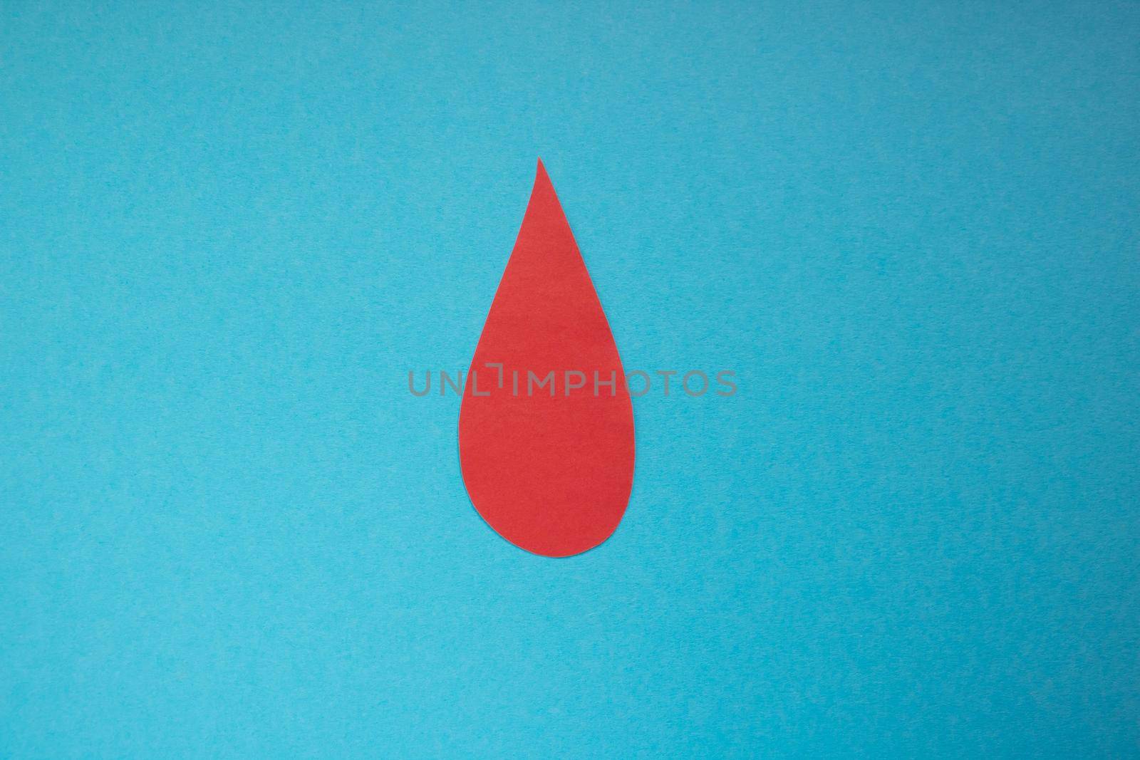 The concept of the World Blood Donor and Hemophilia Day. Red paper drop of blood on a blue background.