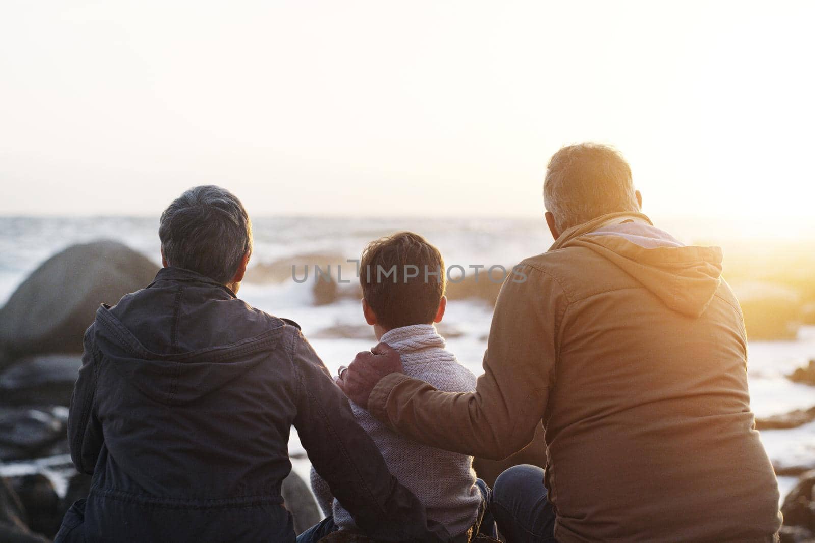 Precious moments at the beach. Rearview shot a little boy and his grandparents relaxing at the beach. by YuriArcurs