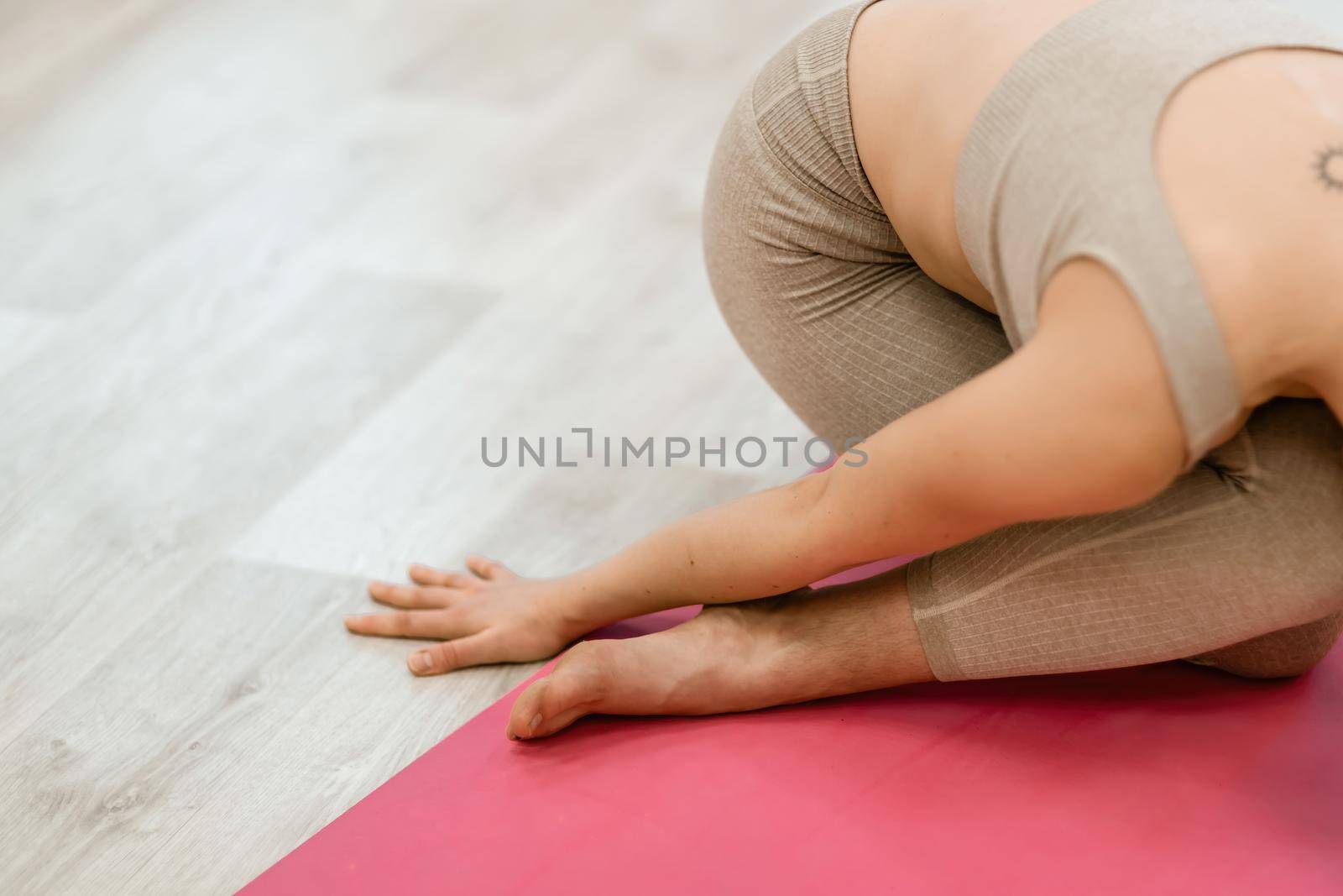 Girl does yoga. Young woman practices asanas on a beige one-ton background. by Matiunina