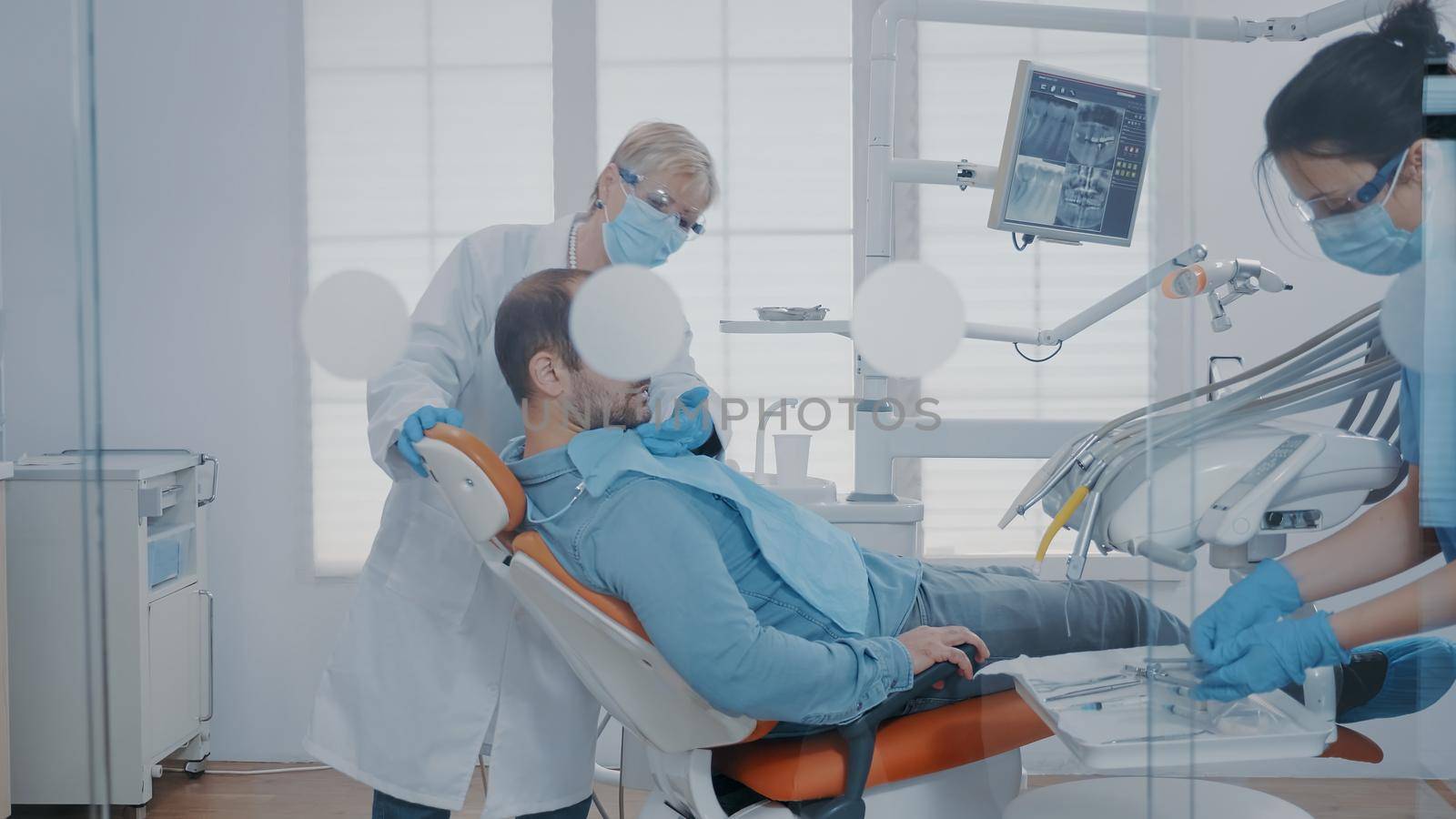 Stomatologist examining patient with mouth open in cabinet, using dental tools and equipment. Dentistry expert getting ready for surgical procedure to extract painful tooth for oral care.