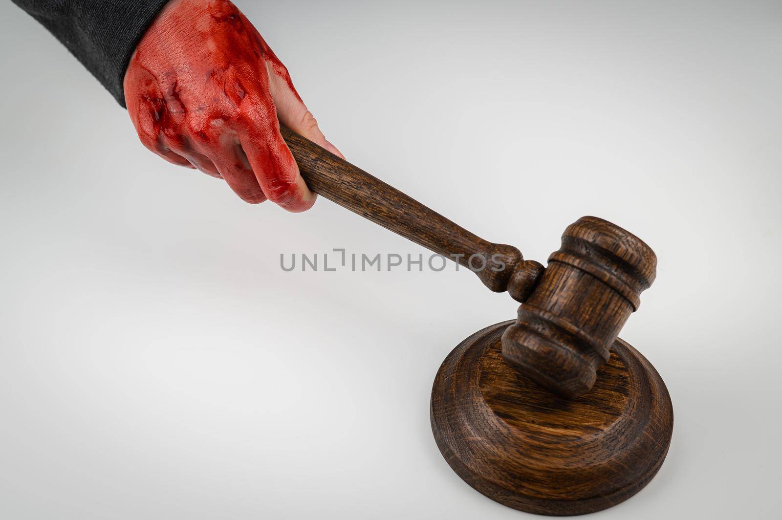 Female judge with bloody hands beats the gavel on a white background. by mrwed54
