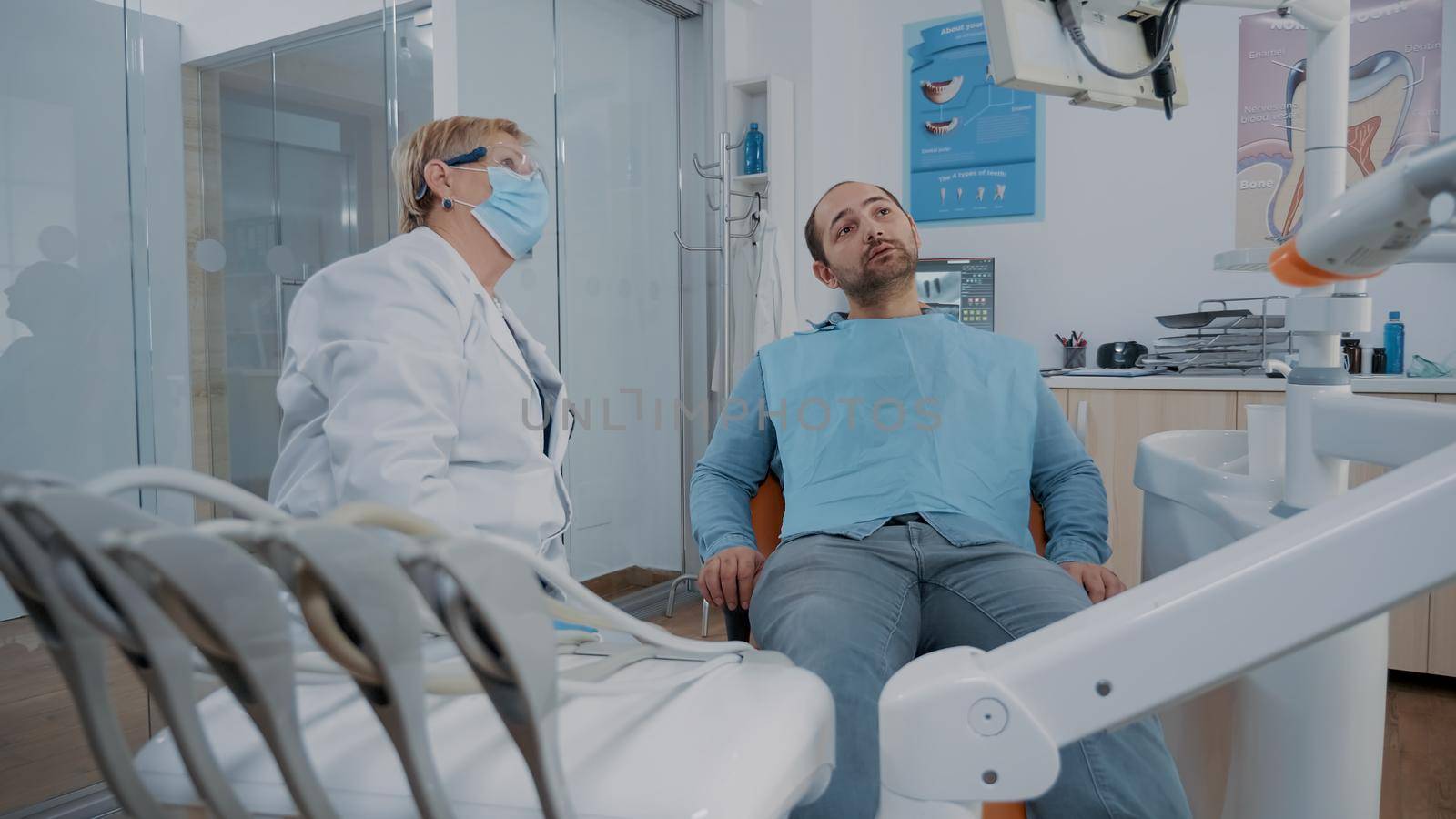 Orthodontist pointing at teeth radiography on monitor to show caries diagnosis to patient in pain. Dentist explaining x ray scan and stomatological procedure to cure toothache.
