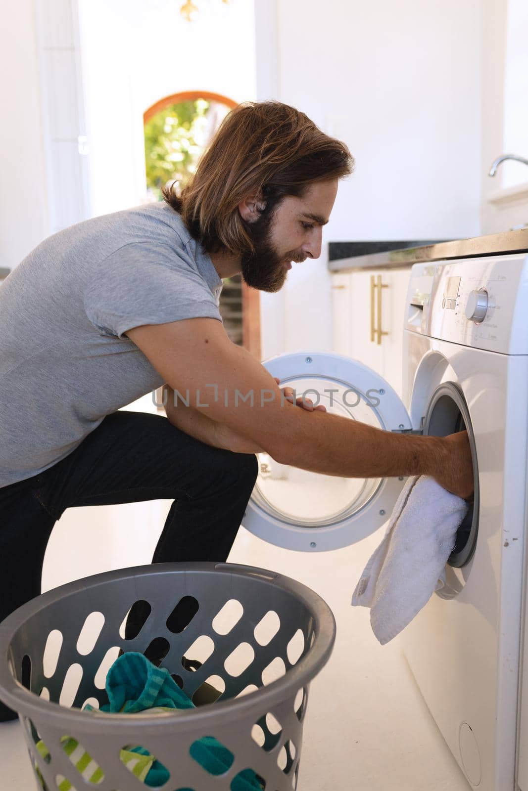 Caucasian man wearing gray tshirt and doing laundry by Wavebreakmedia