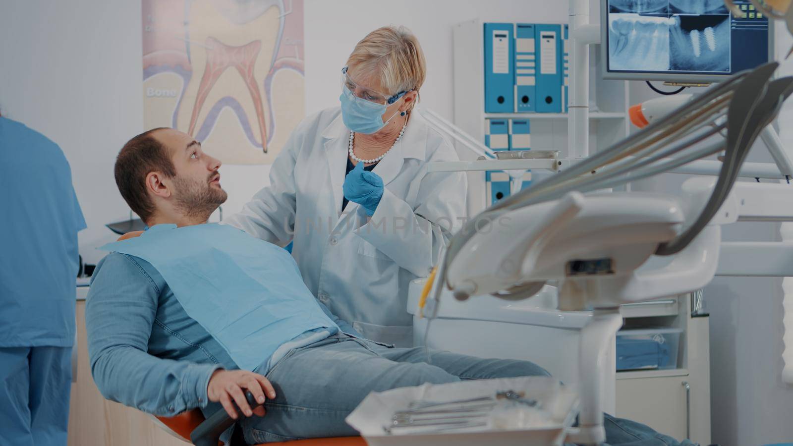 Patient with mouth open receiving examination from dentist by DCStudio