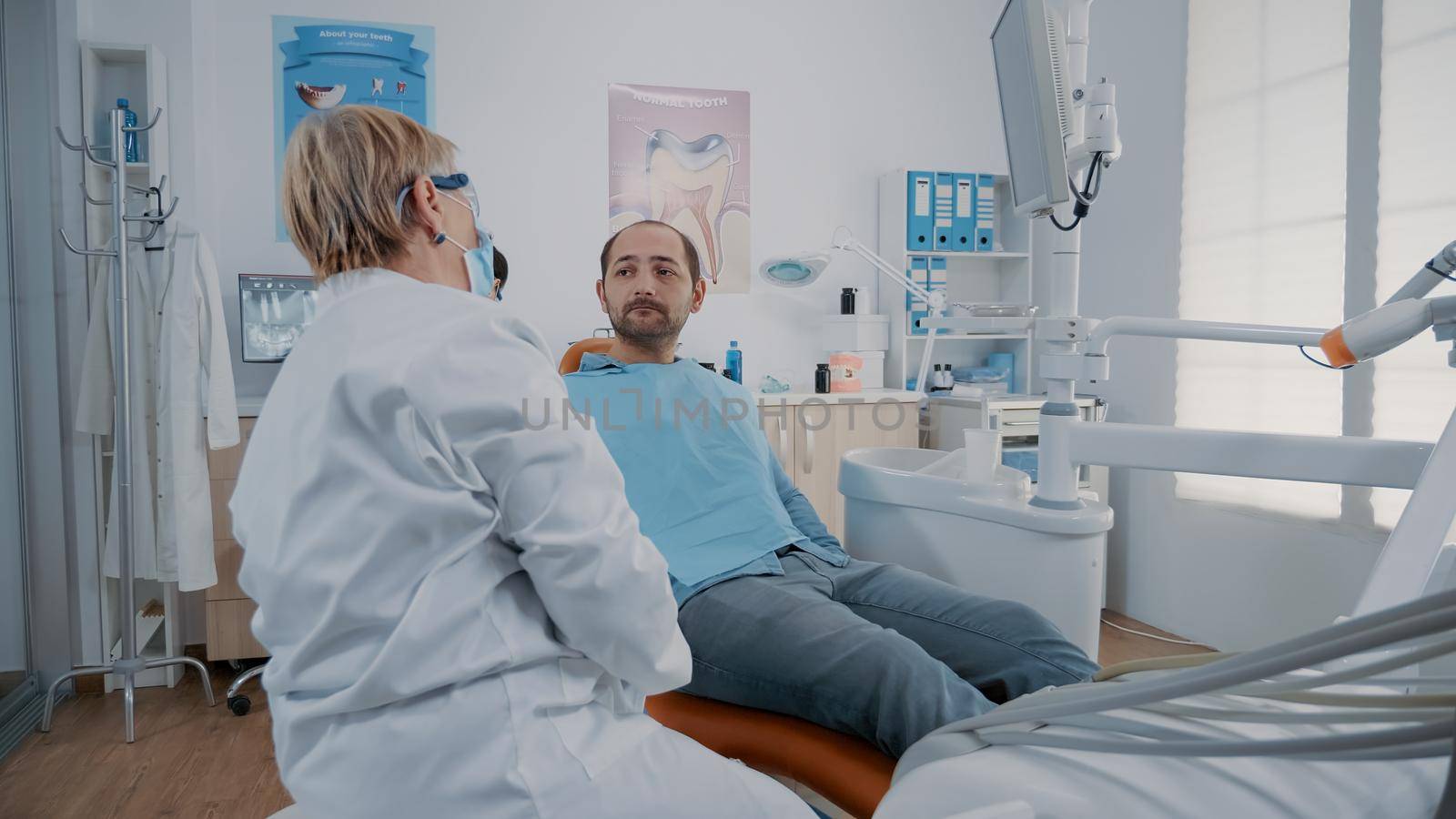 Stomatologist using monitor to show denture x ray scan to man in dentistry cabinet. Medic explaining teeth radiography and test diagnosis to do surgical procedure for oral care.