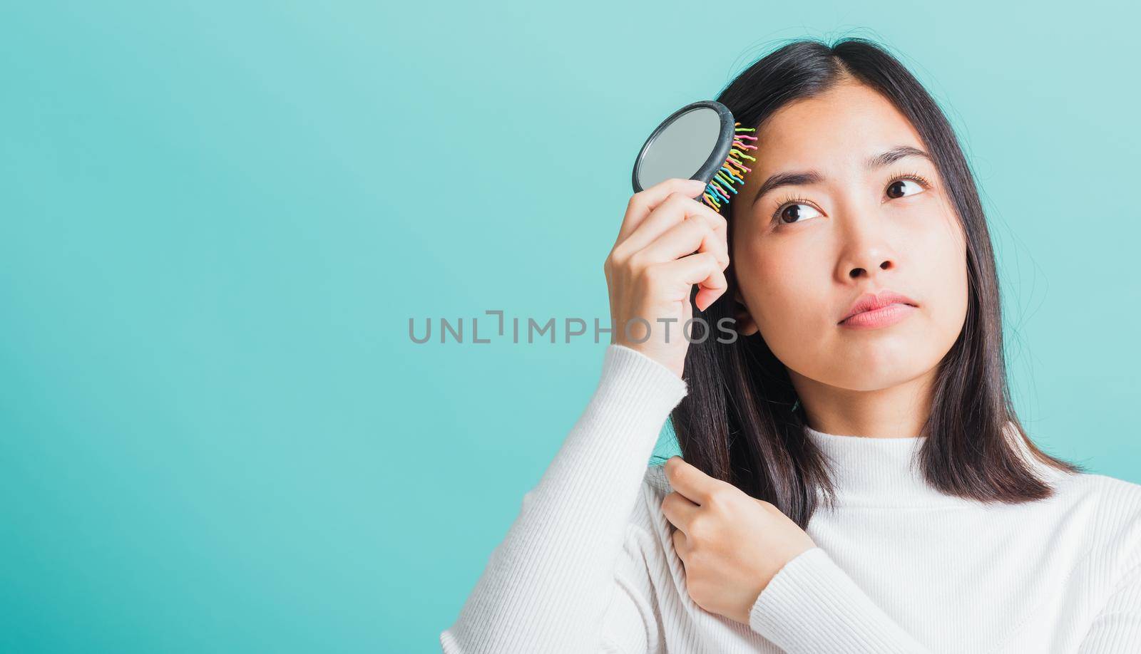 Young beautiful Asian woman upset with a comb and problem hair, Portrait female shocked suffering from hair loss problem, studio shot isolated on a blue background, medicine health concept