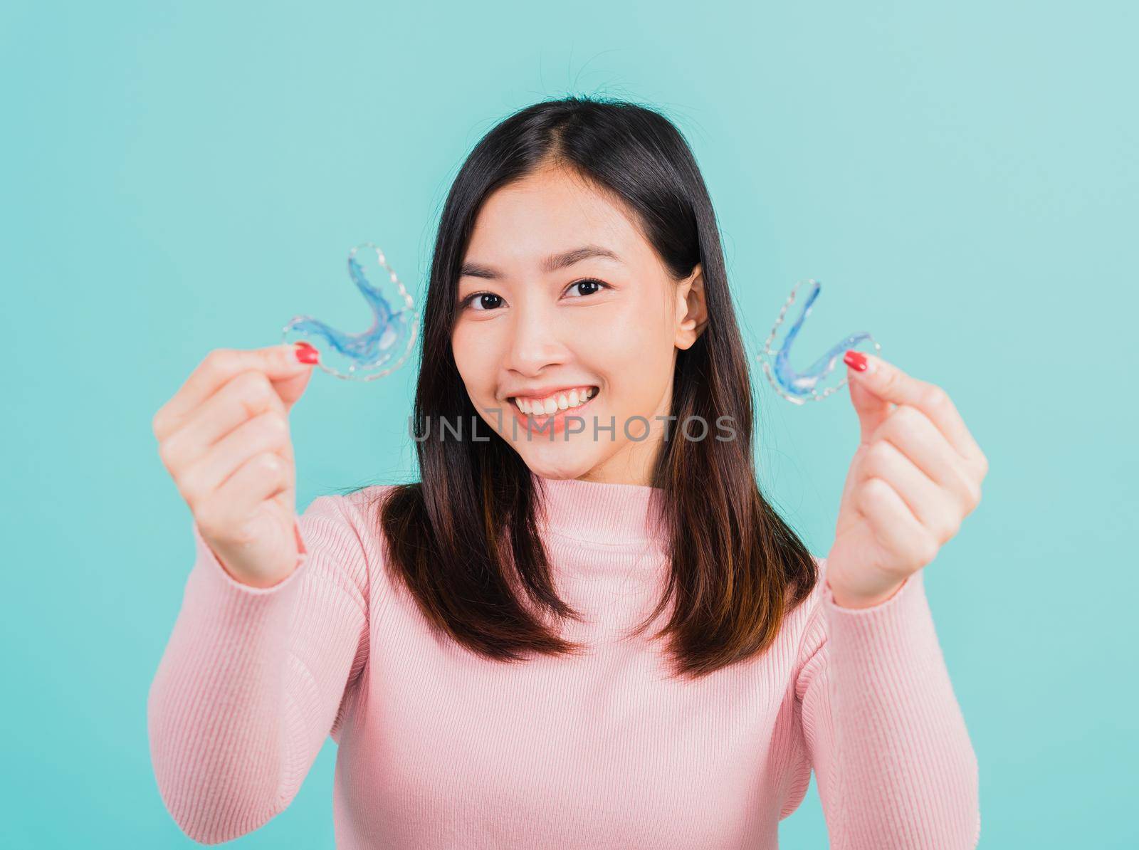 woman smiling hold silicone orthodontic retainers for teeth by Sorapop
