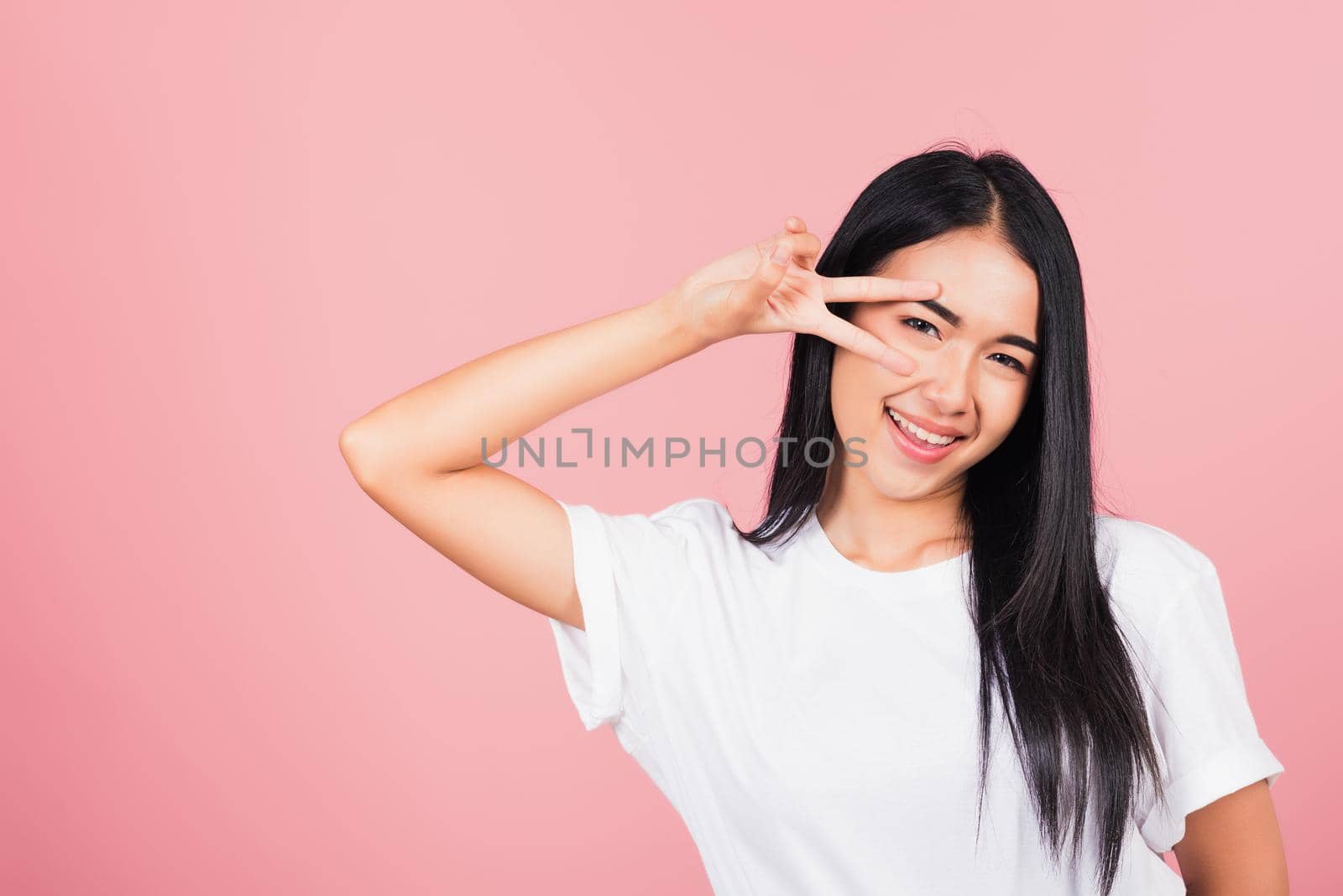 Asian happy portrait beautiful cute young woman teen smile standing showing finger making v-sign victory by Sorapop