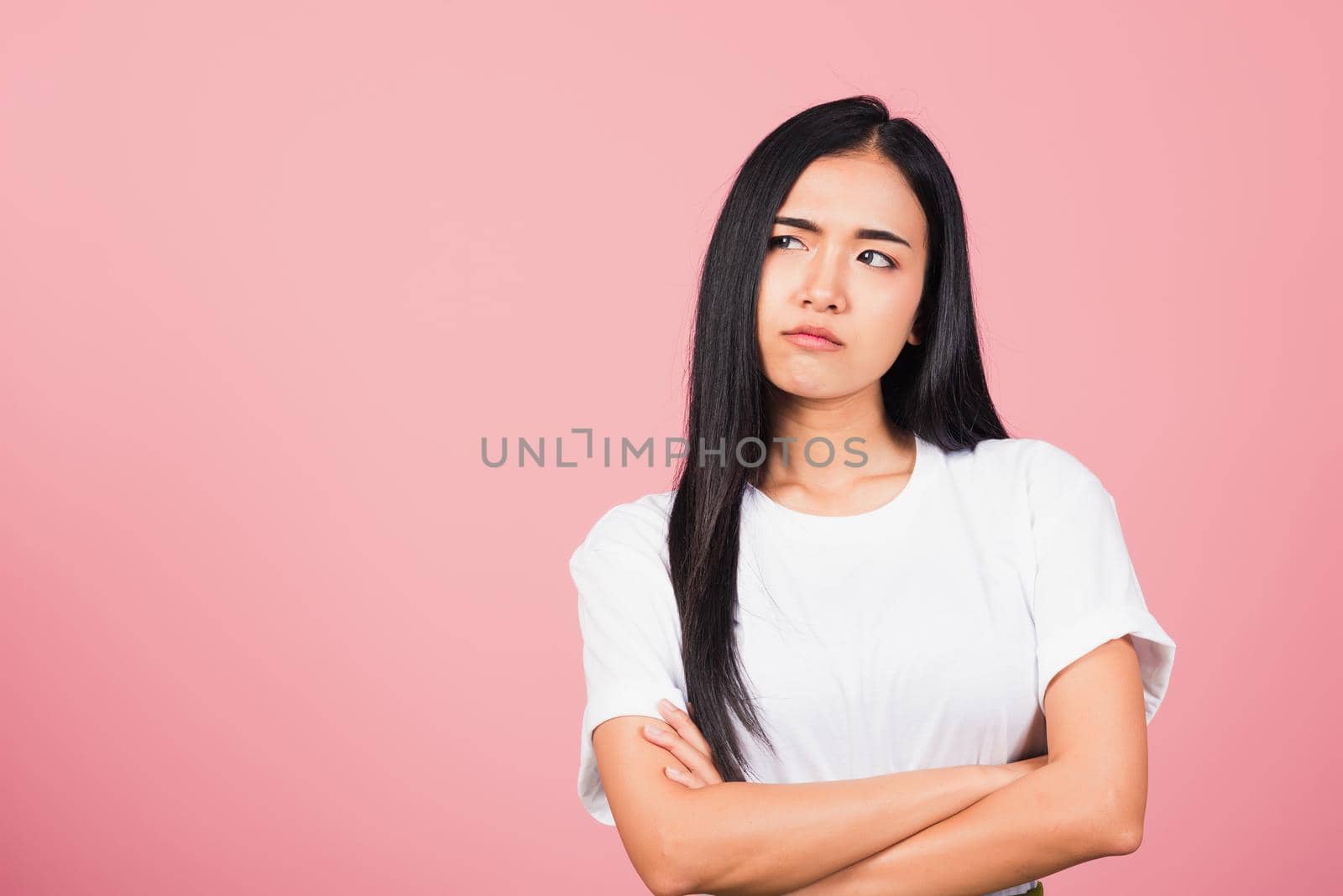 Asian happy portrait beautiful cute young woman standing with crossed arms angry and mad raising fist frustrated and furious while shouting with anger isolated, studio shot on pink background