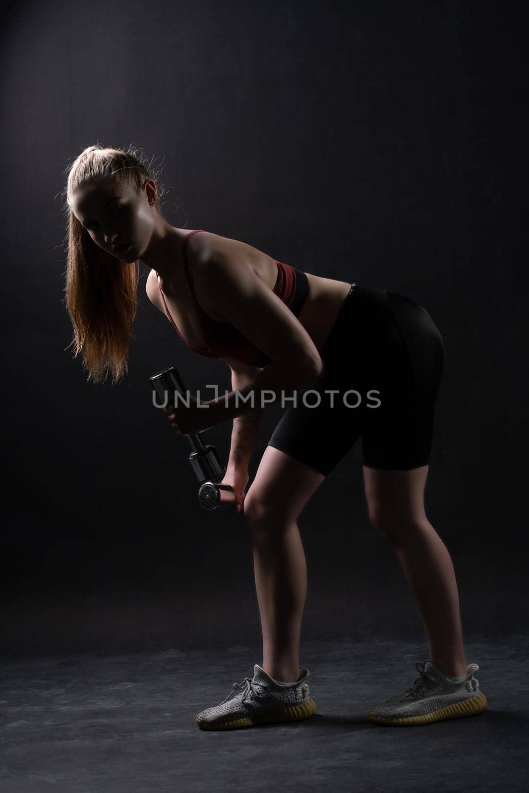 Girl A dumbbells with beautiful stands on a black background Keira Knightley girl dumbbells fitness body, from female fit for exercise from active strength, sexy biceps. Sweat weight beauty