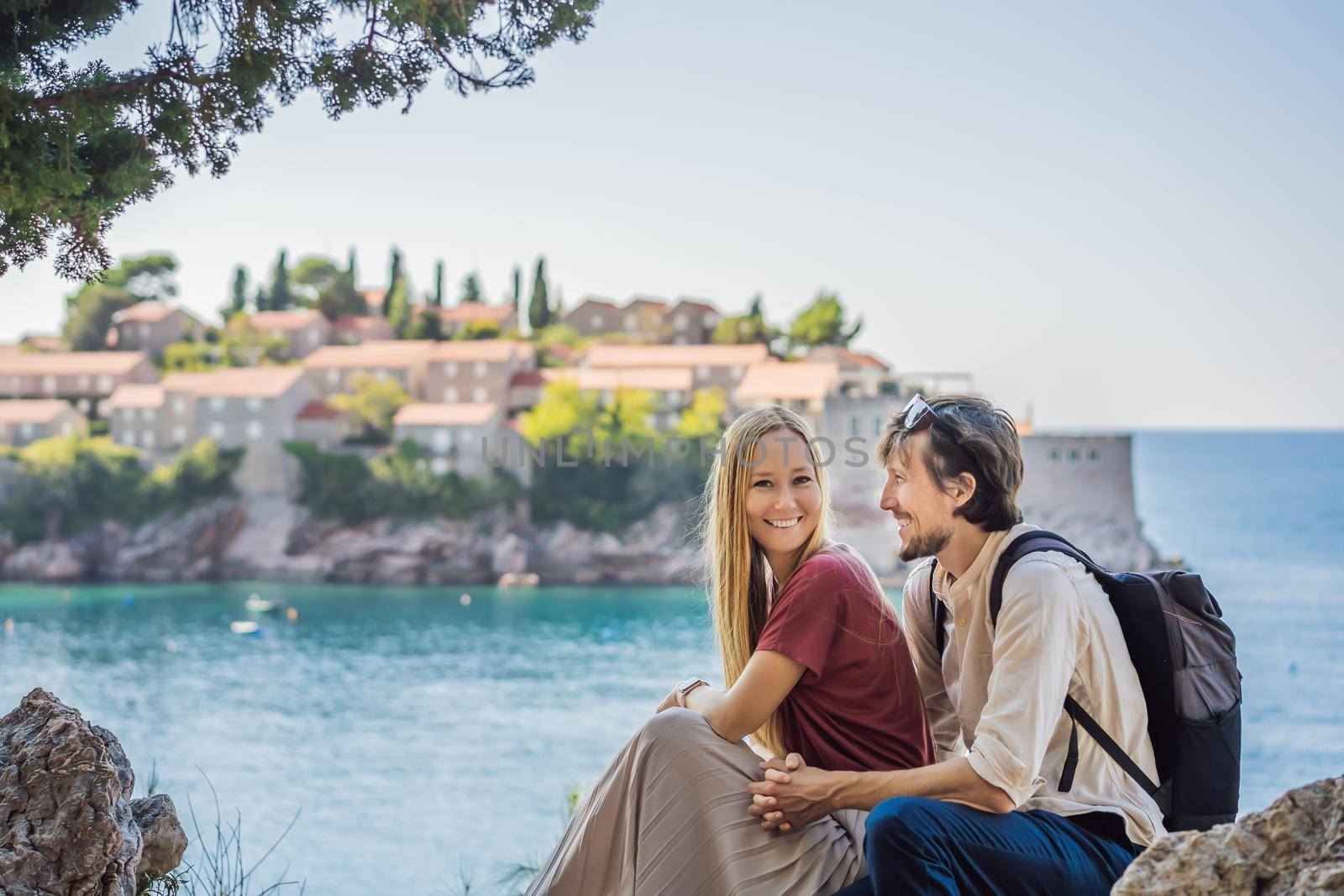 Man and woman tourists on background of beautiful view of the island of St. Stephen, Sveti Stefan on the Budva Riviera, Budva, Montenegro. Travel to Montenegro concept.