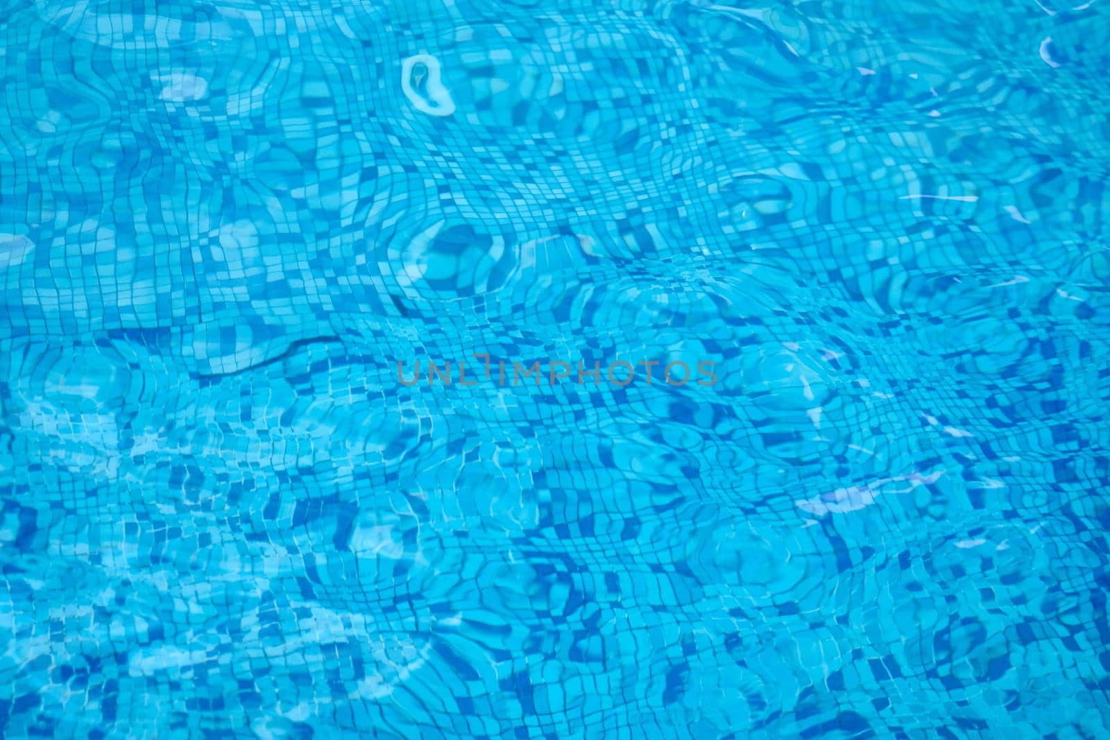 Background of water in blue swimming pool, water surface with sun reflection