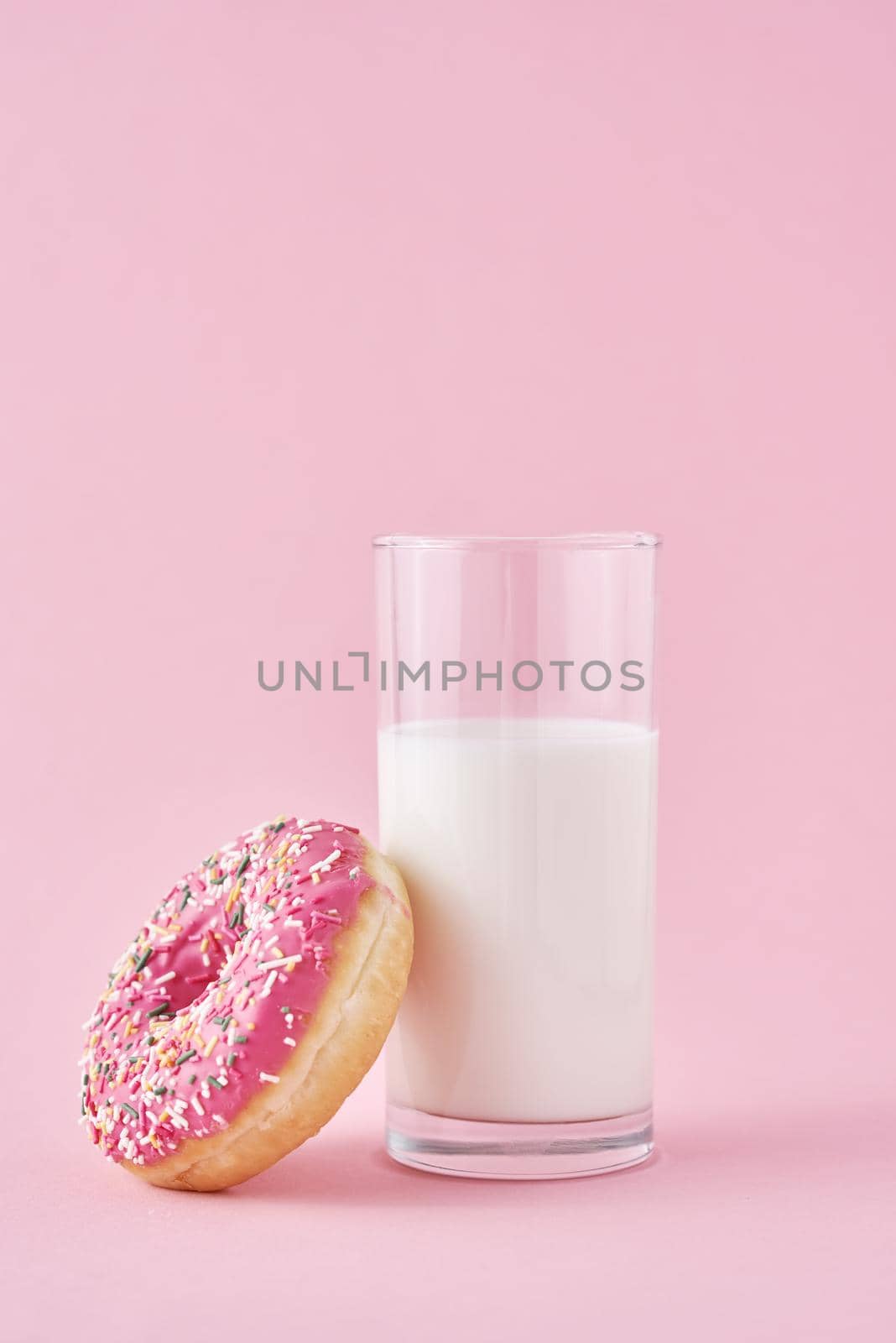 Donuts with glass of milk on pink background