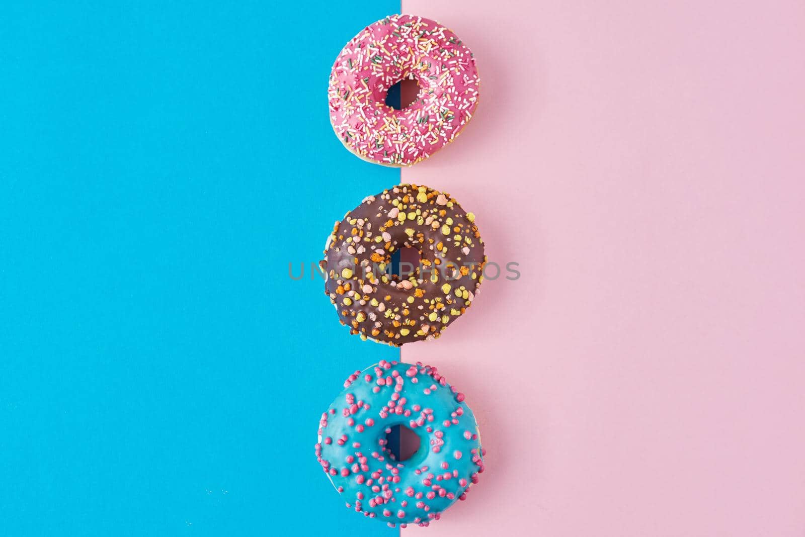 Donuts on pastel pink and blue background. Minimalism creative food composition. Flat lay style