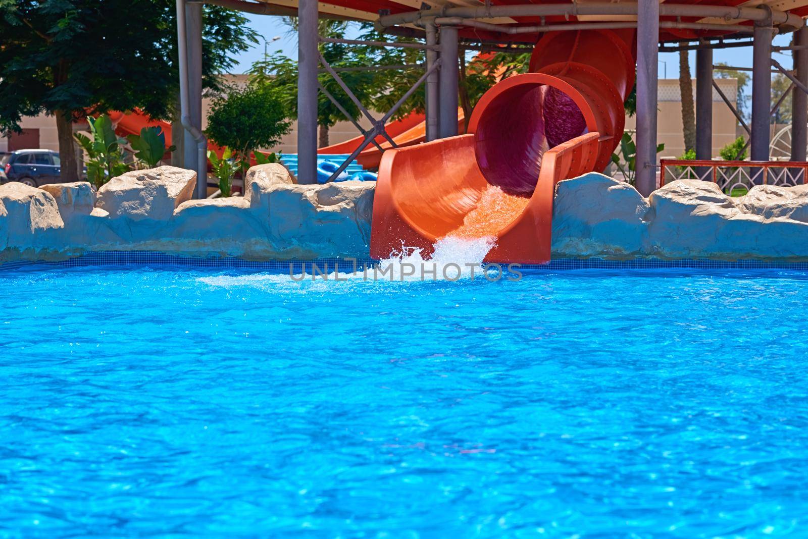 Red water park slide and swimming pool. Aqua park background