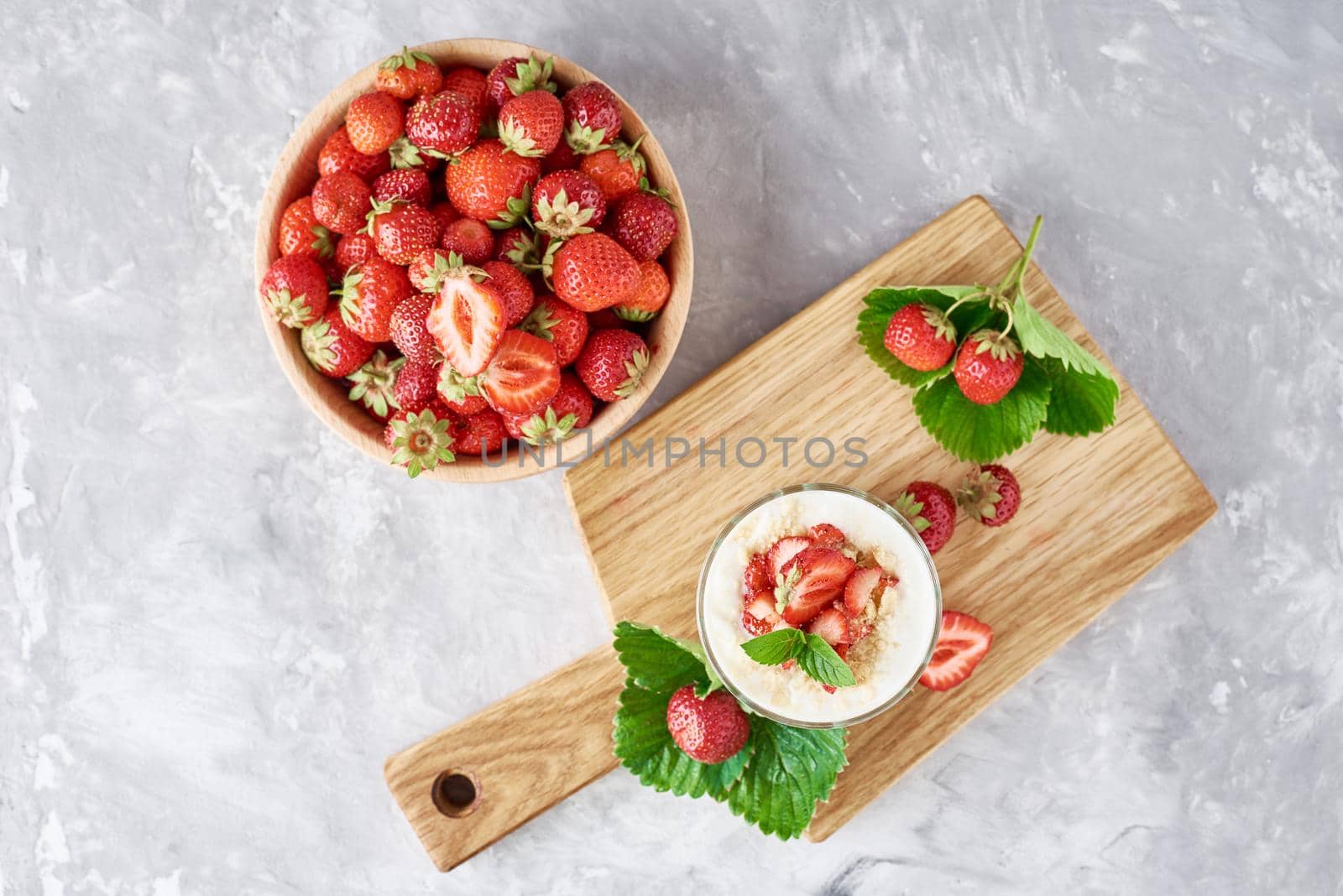 Strawberry granola or smoothie in glass and fresh berries in wooden bowl, top view. Healthy breakfast