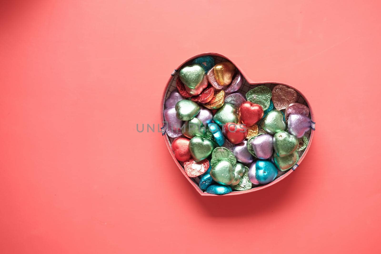 small heart shape gift with candy on red background