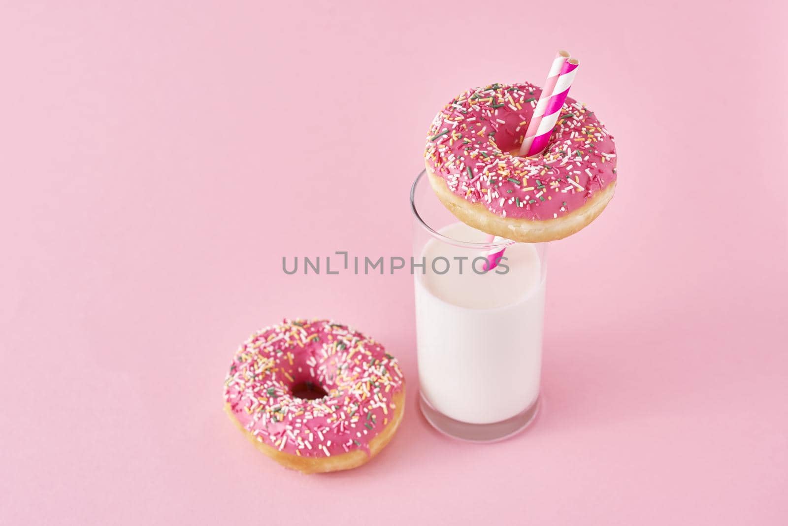 Donuts with glass of milk on pink background