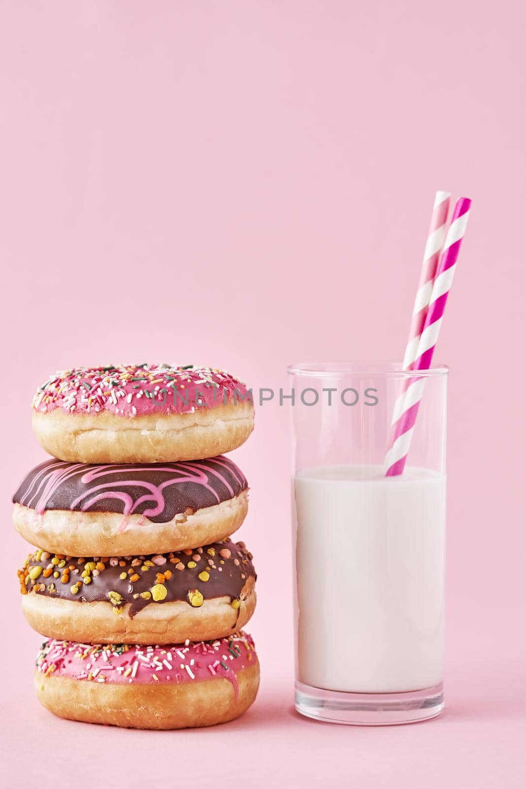 Stack of colorful donuts decorated and glass of milk on a pink background by Lazy_Bear