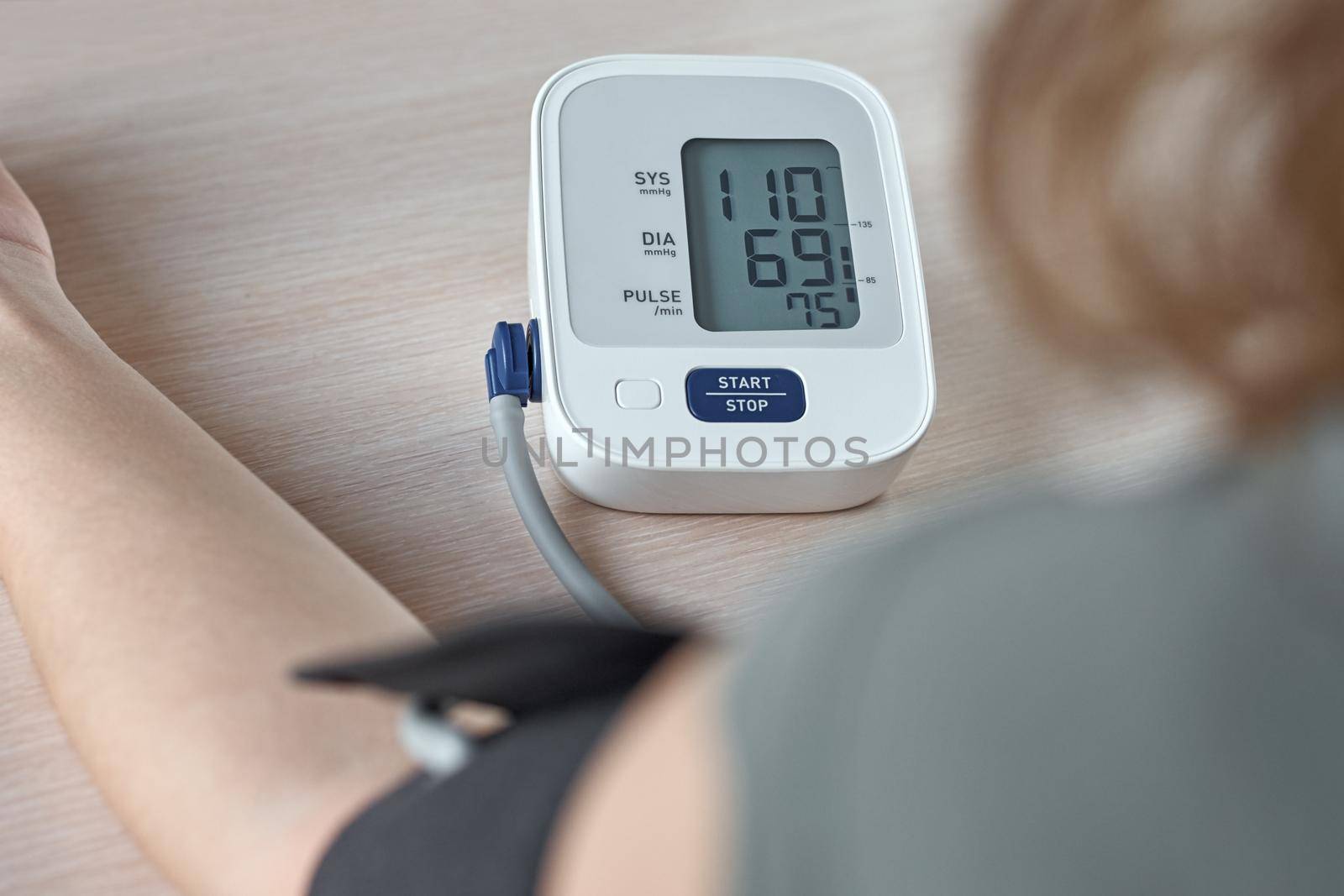 Woman measuring blood pressure with an electric digital monitor. Healthcare and medicine concept by Lazy_Bear