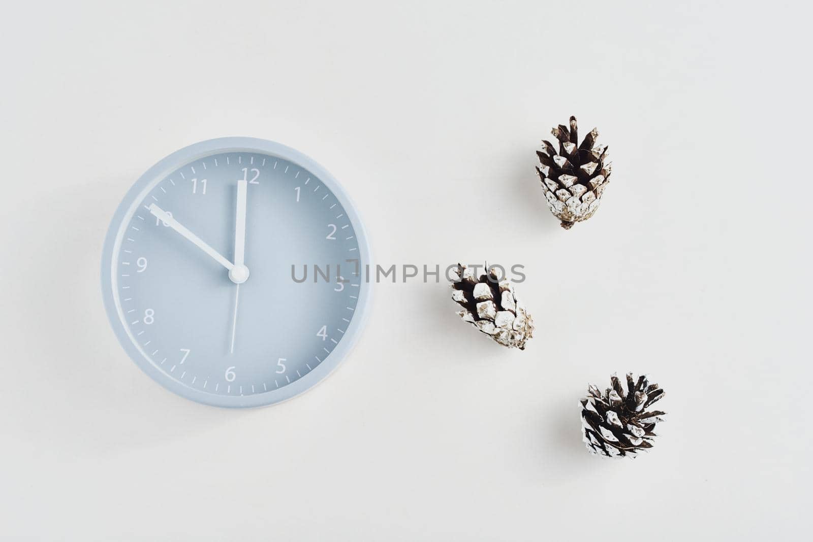 Alarm clock with a pine cones on white background, top view. Minimal creativity flat lay style by Lazy_Bear