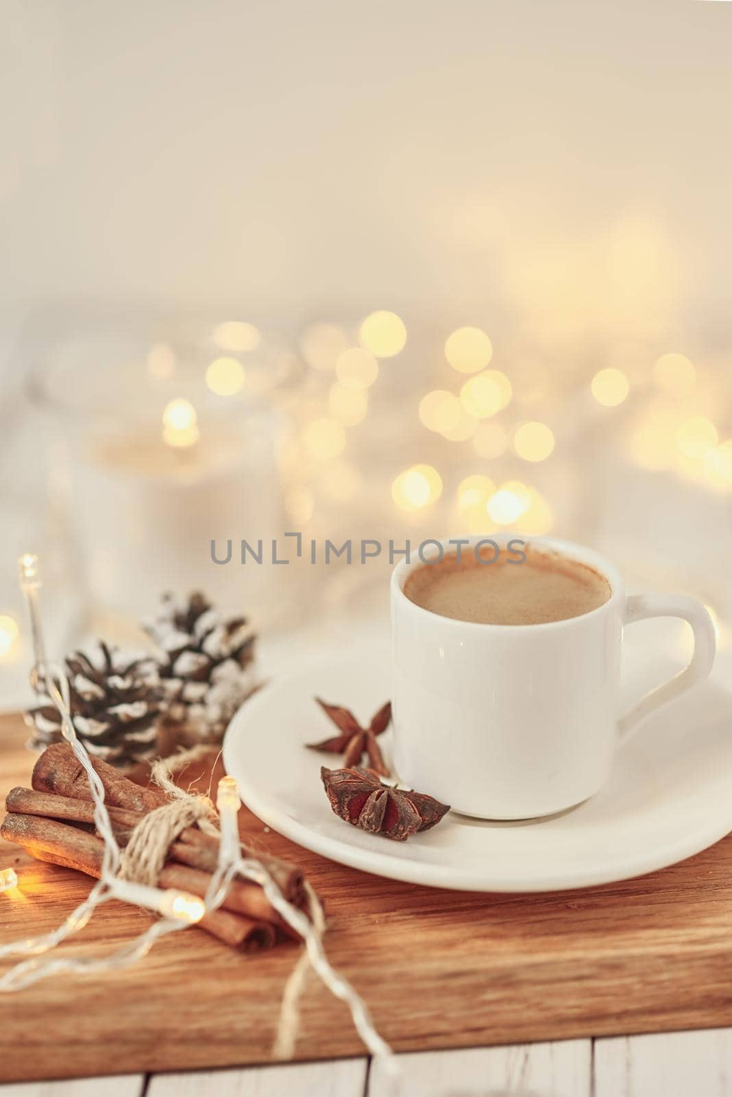 Cup of coffee with garland lights and decoration on table. Cozy home concept