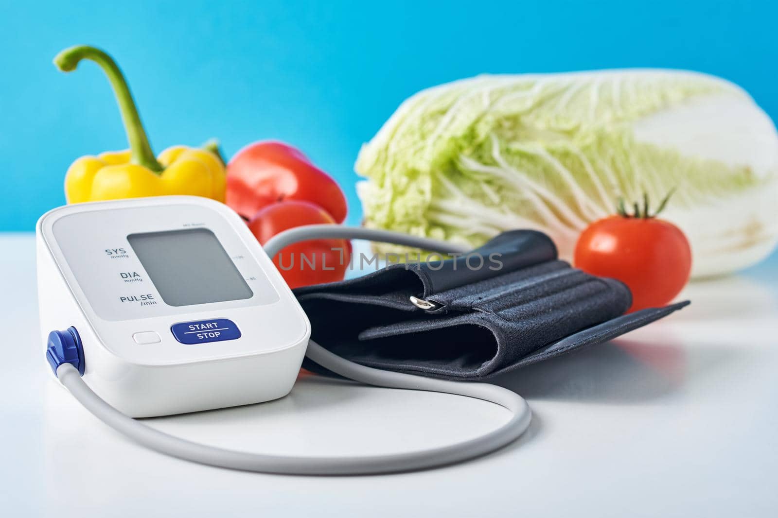 Digital blood pressure monitor and fresh vegetables on the table against blue background. Healthcare concept by Lazy_Bear