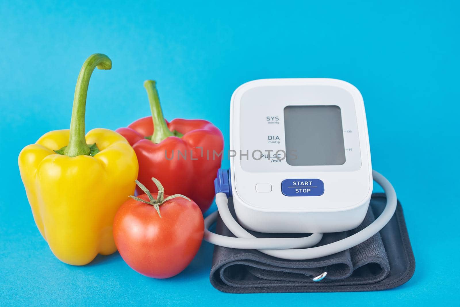 Digital blood pressure monitor and fresh vegetables on a blue background. Healthcare concept by Lazy_Bear