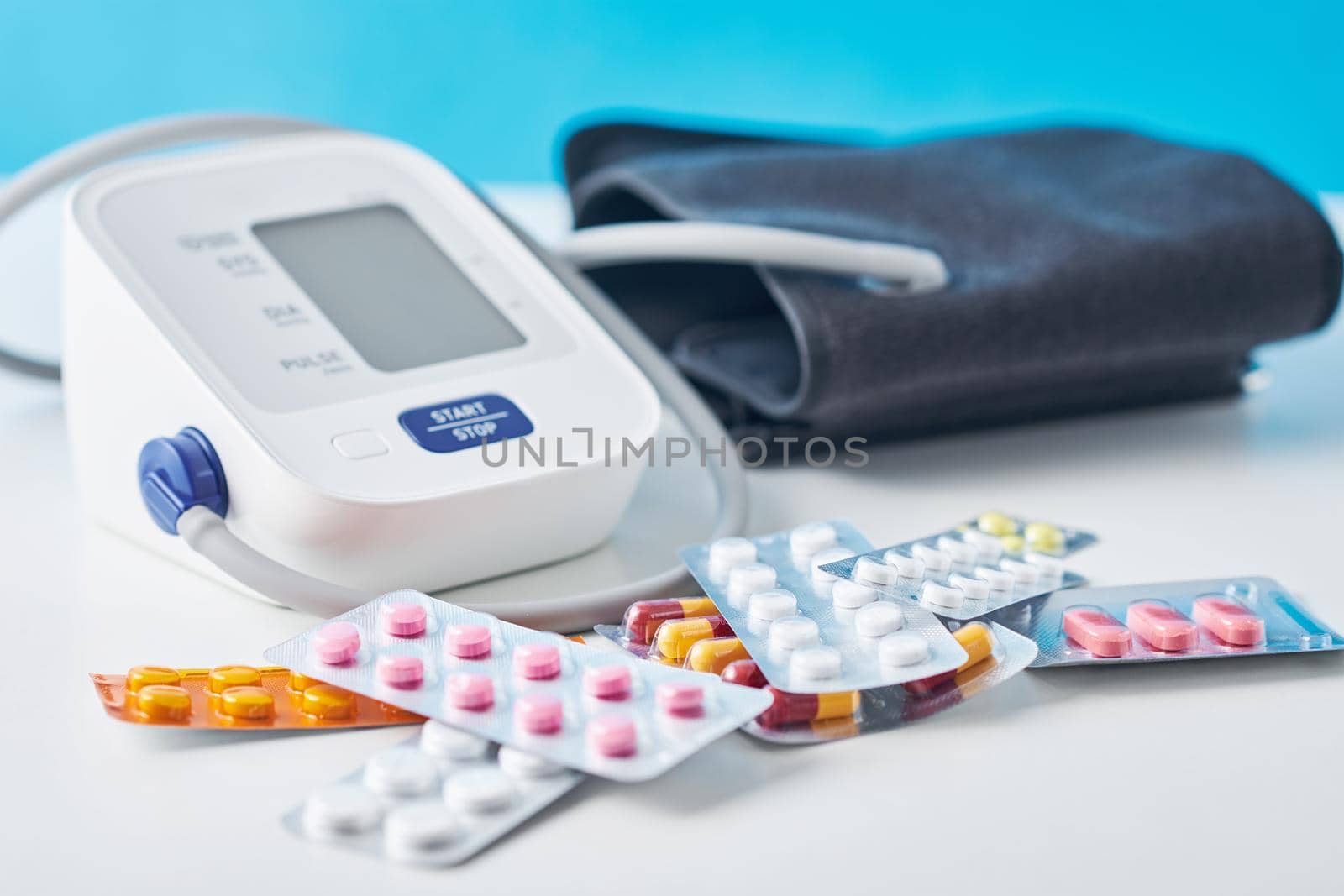 Digital blood pressure monitor and medical pills on the white table. Healthcare and medicine concept by Lazy_Bear