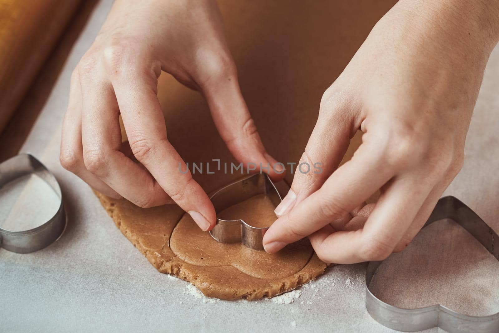 Making gingerbread cookies in the shape of a heart for Valentines Day. Woman hand use cookie cutter. Holiday food concept by Lazy_Bear