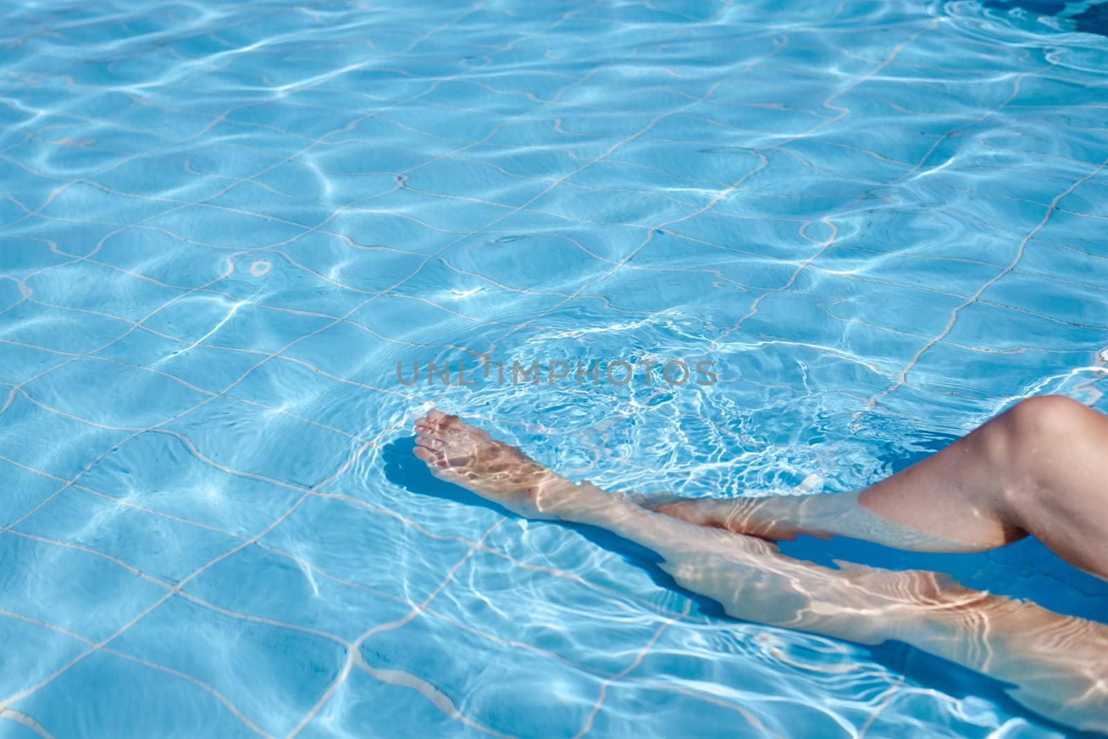 Female legs in water pool. Summer holiday