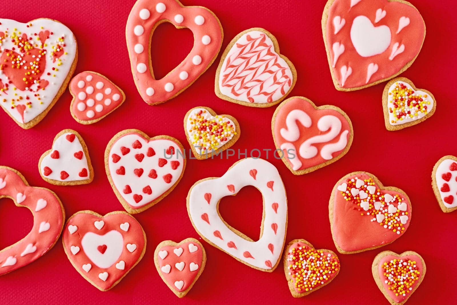 Background of decorated with icing and glazed heart shape cookies on the red background, flat lay. Valentines Day food concept by Lazy_Bear