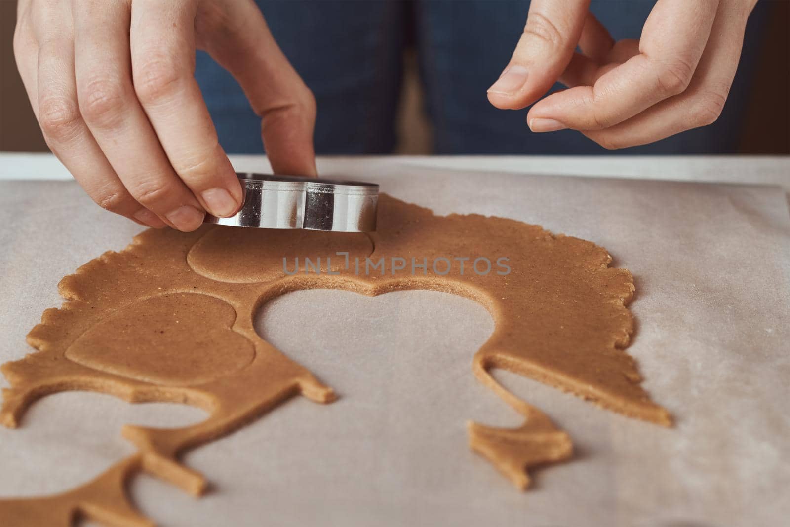 Making gingerbread cookies in shape of a heart for Valentines Day. Woman hand use cookie cutter. Holiday food concept