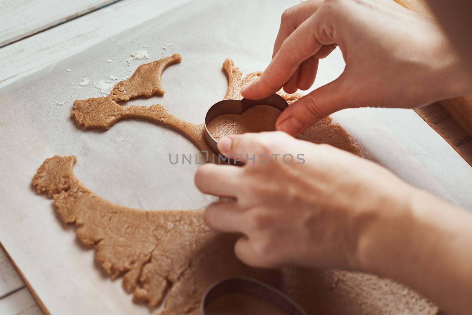 Making gingerbread cookies in shape of a heart for Valentines Day. Woman hand use cookie cutter. Holiday food concept