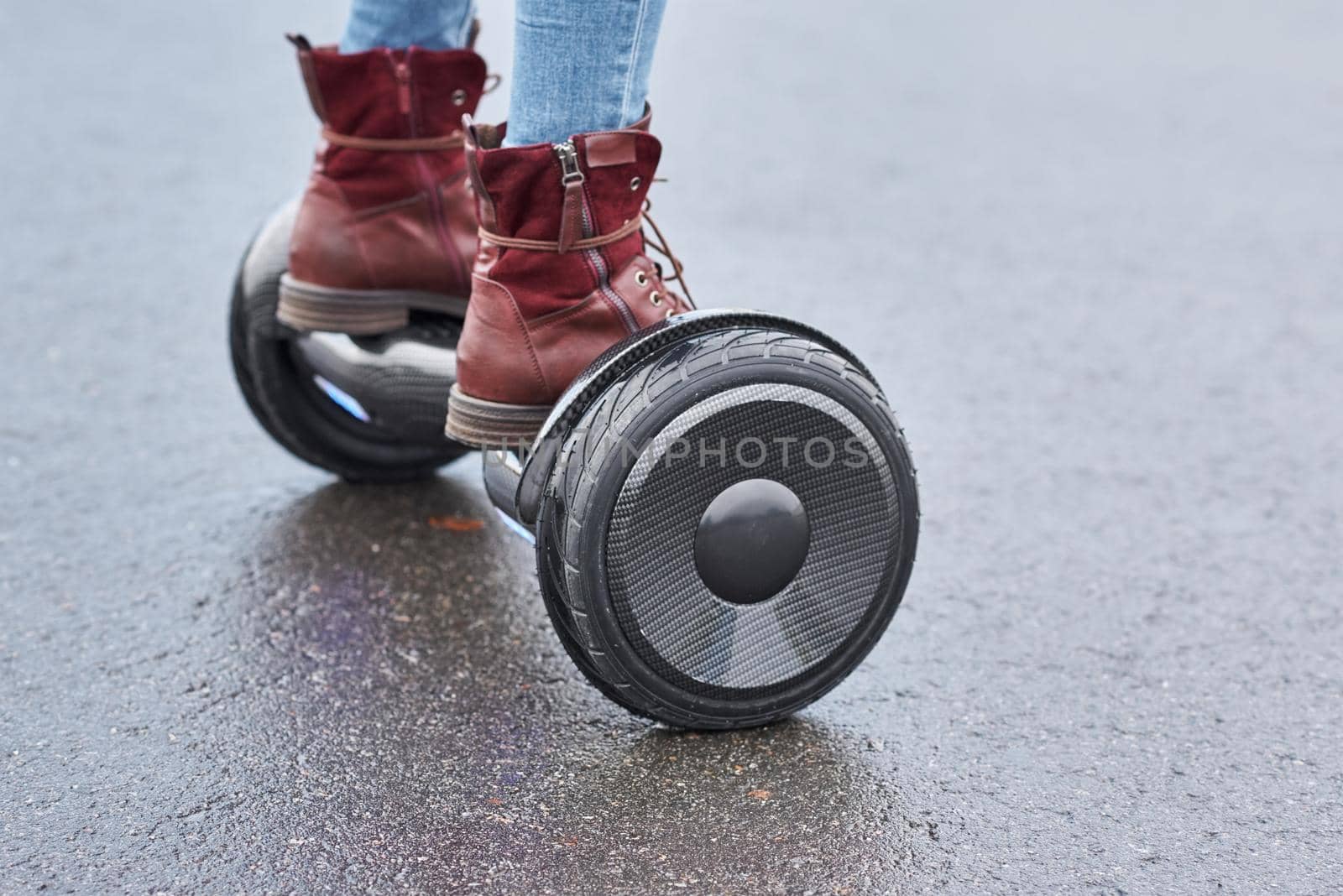 Close up of woman using hoverboard on asphalt road. Feet on electrical scooter outdoor by Lazy_Bear