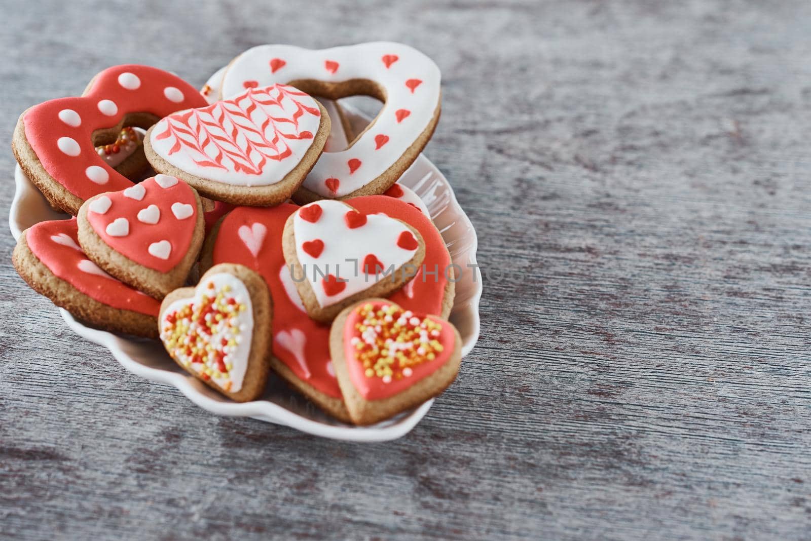 Decorated heart shape cookies in plate on gray background. Valentines Day food concept