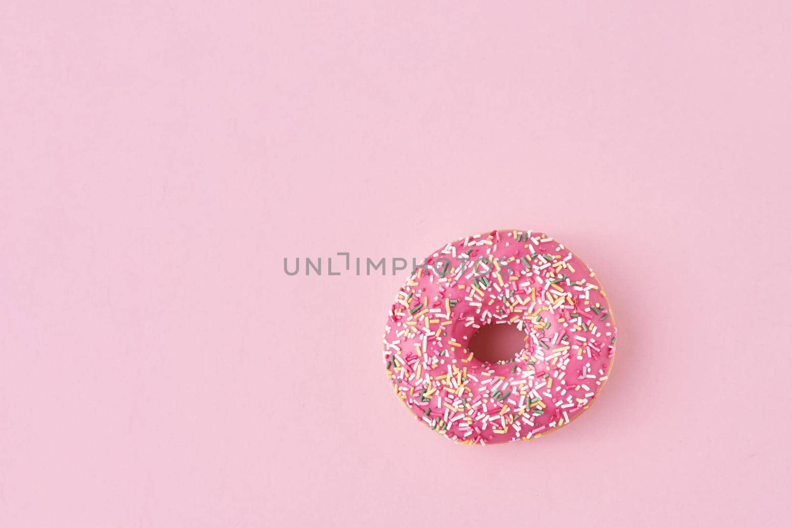 donats decorated sprinkles and icing on pink background. Creative and minimalis food concept, top view flat lay