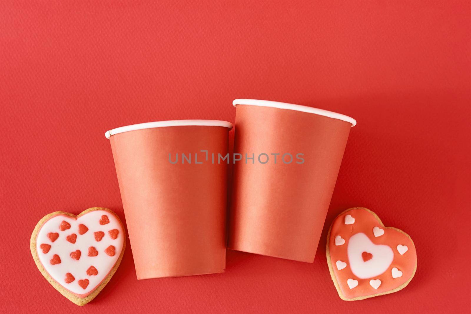 Decorated heart shape cookies and two paper coffee cups on red background. Valentines Day food concept