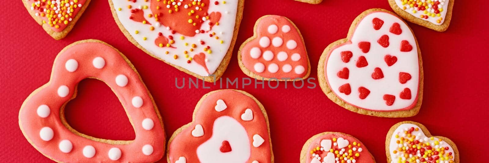 Background of decorated with icing and glazed heart shape cookies on the red background, long banner. Valentines Day food concept by Lazy_Bear