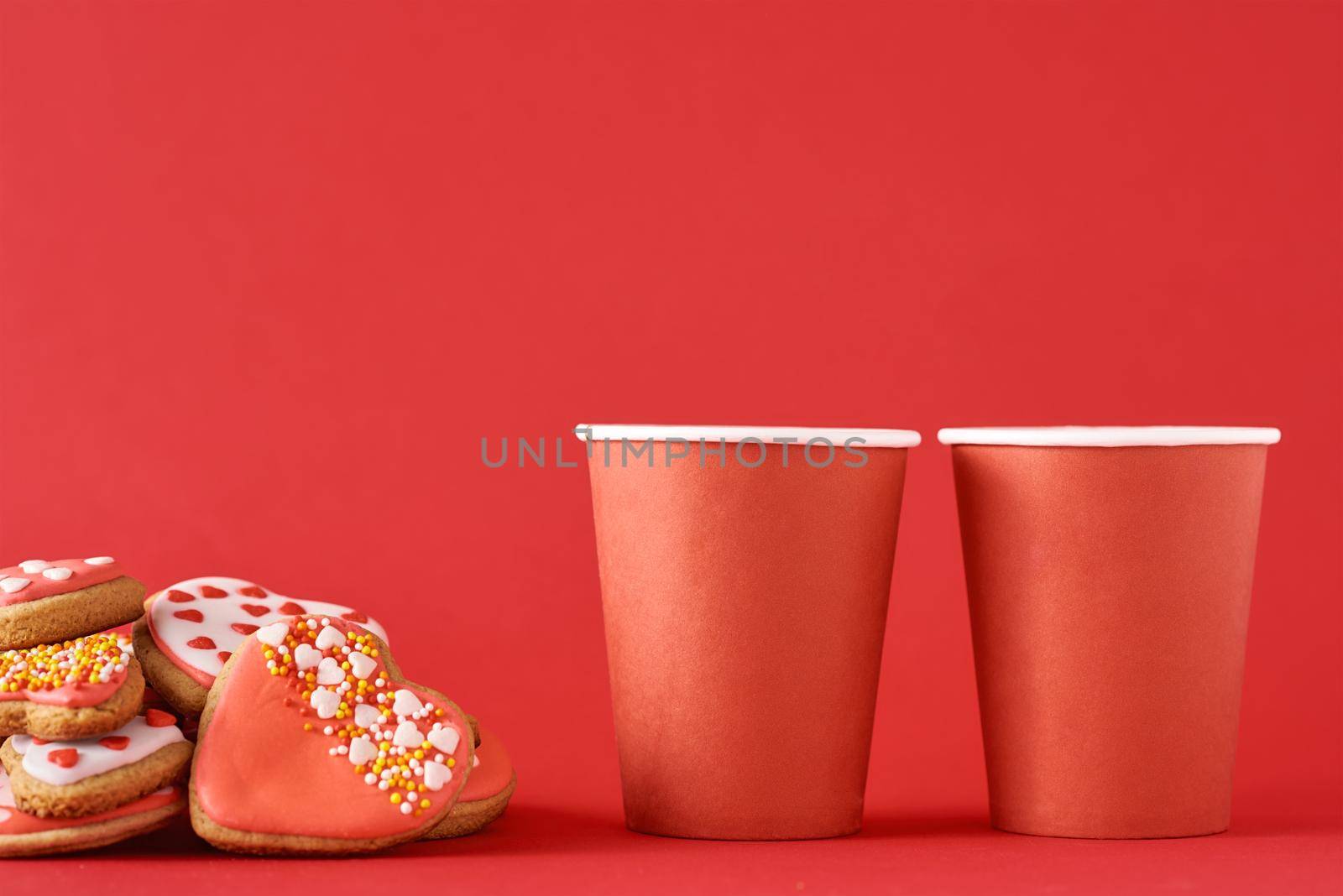 Decorated heart shape cookies and two paper coffee cups on the red background. Valentines Day food concept by Lazy_Bear