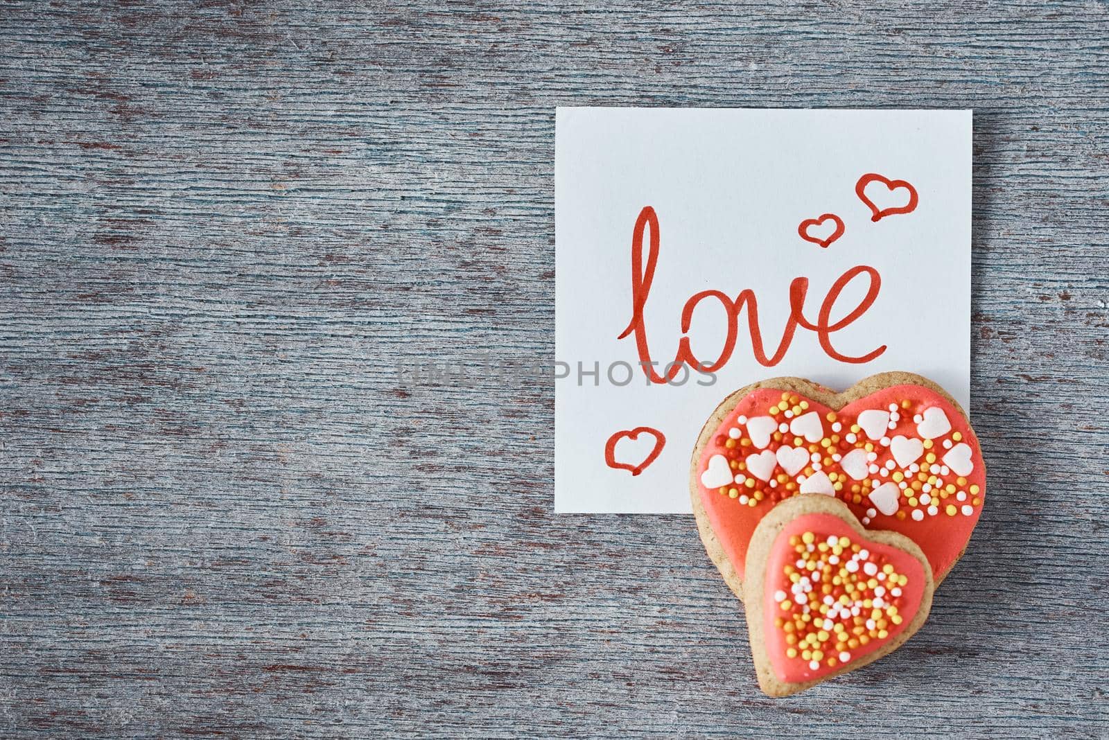 Decorated and glazed heart shape cookies and paper note with inscription LOVE on the gray background, top view. Valentines day concept by Lazy_Bear