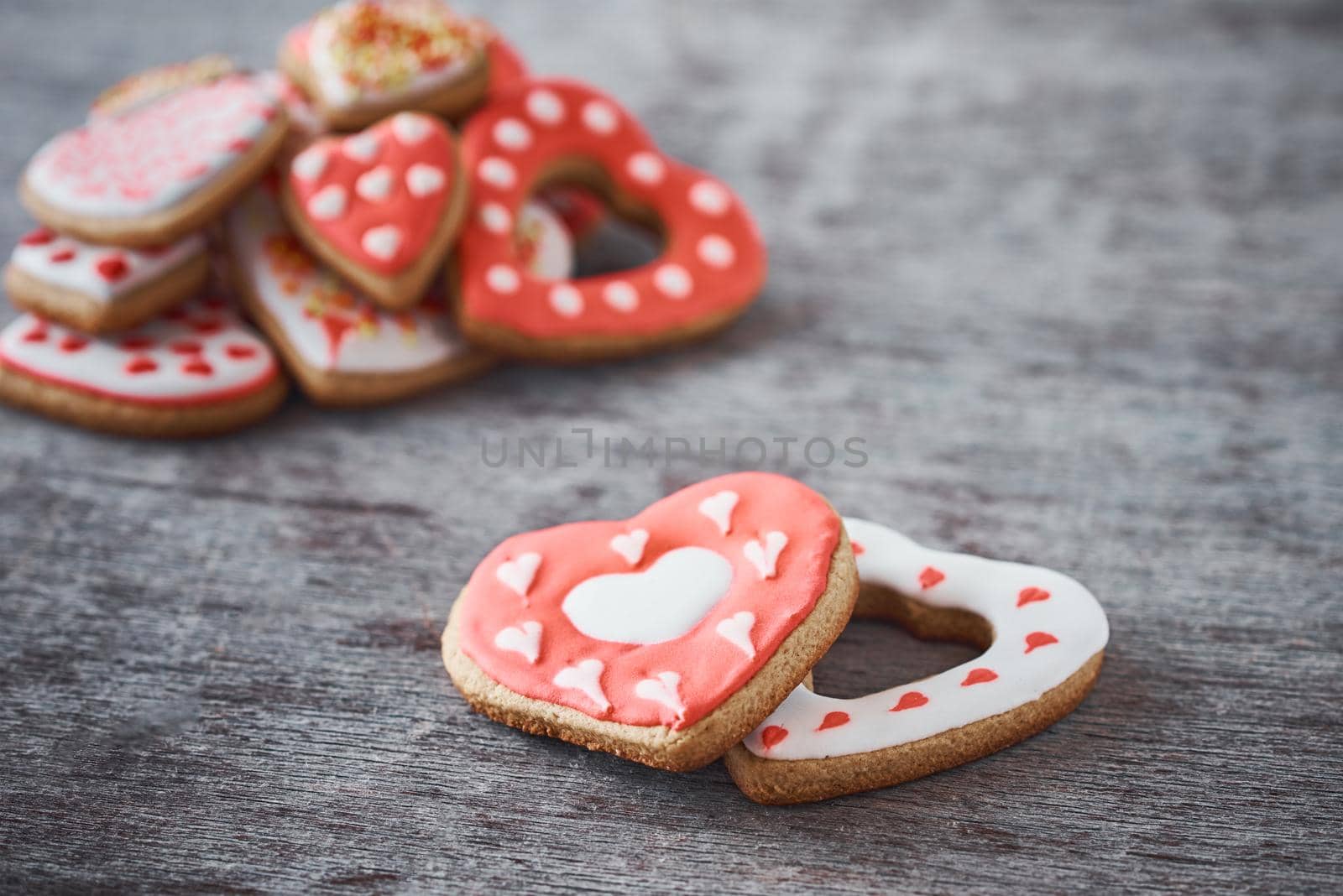 Two heart shape cookies and many decorated cookies on gray background. Valentines Day concept