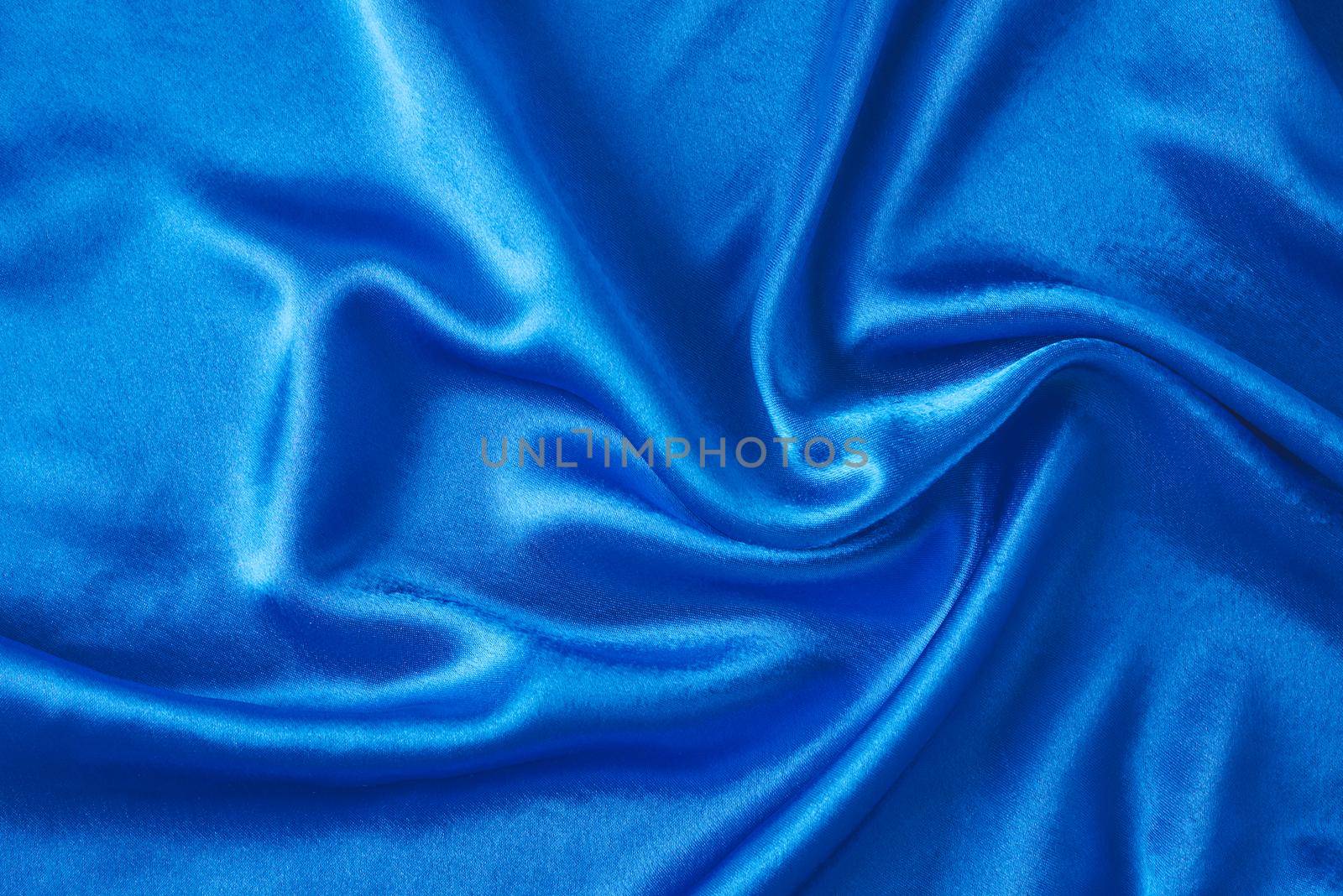 Blue silk background with folds. Abstract texture of rippled satin surface