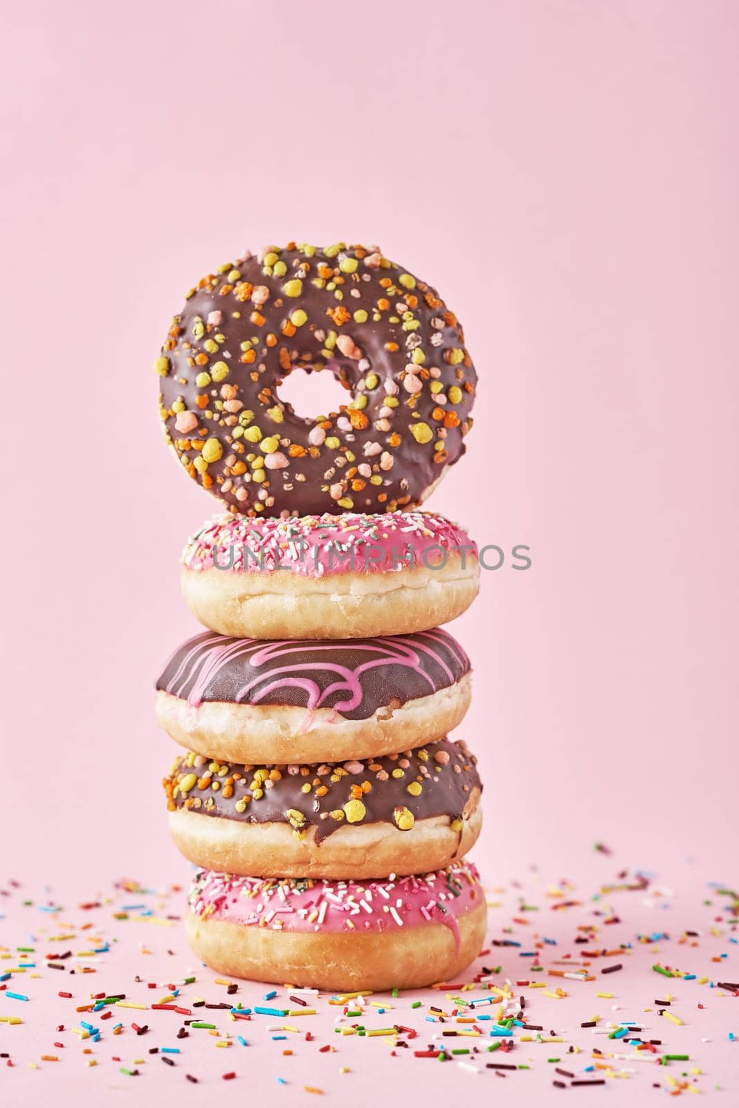 Stack of colorful donuts decorated on pink background