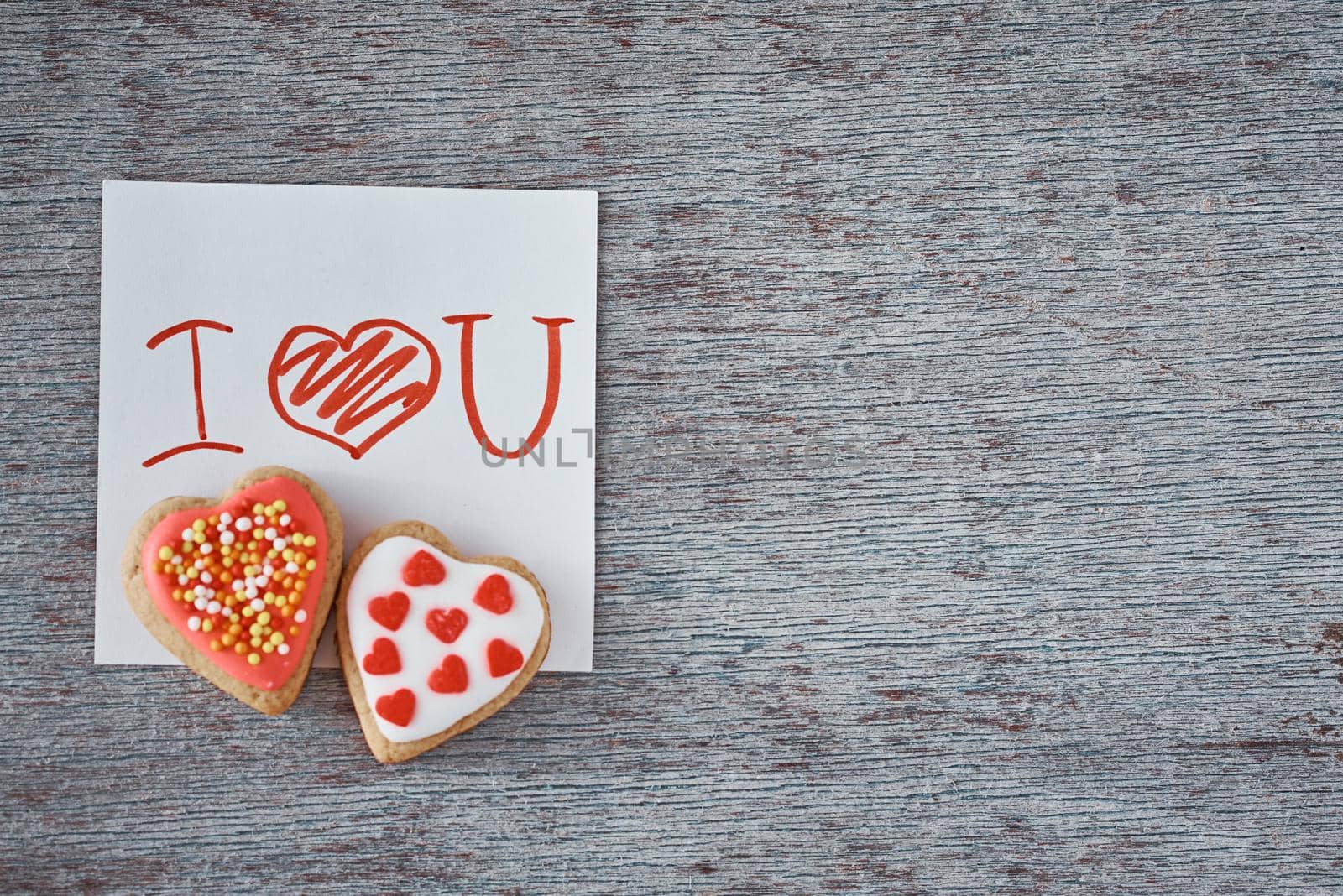 Two heart shape cookies and paper sheet with inscription i love you on gray background. Valentines Day concept