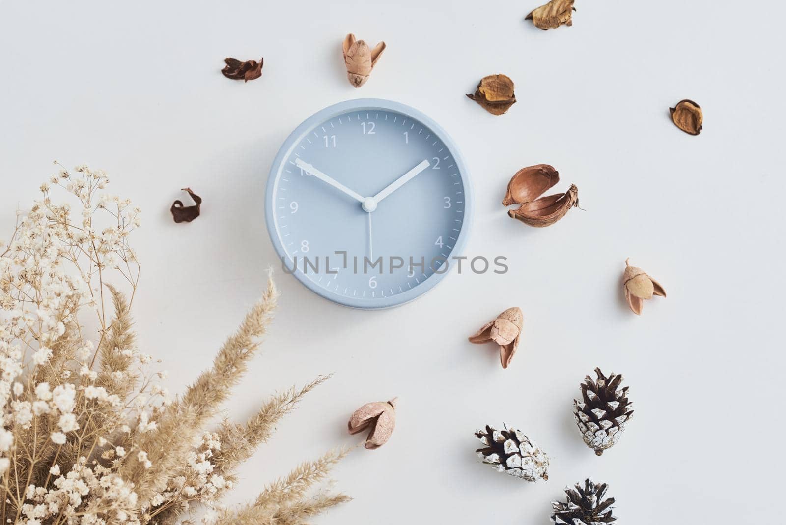 Alarm clock with decorations on white background, top view. Minimal flat lay style