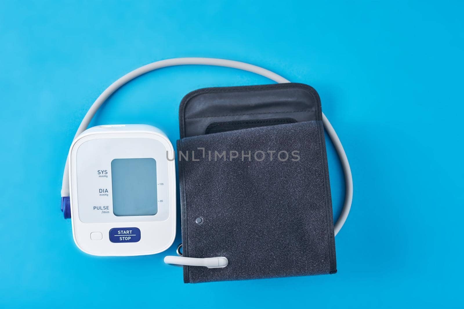 Digital blood pressure monitor on blue background, closeup. Helathcare and medical concept