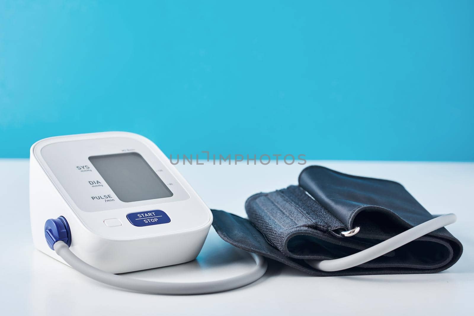Digital blood pressure monitor on blue background, closeup. Helathcare and medical concept