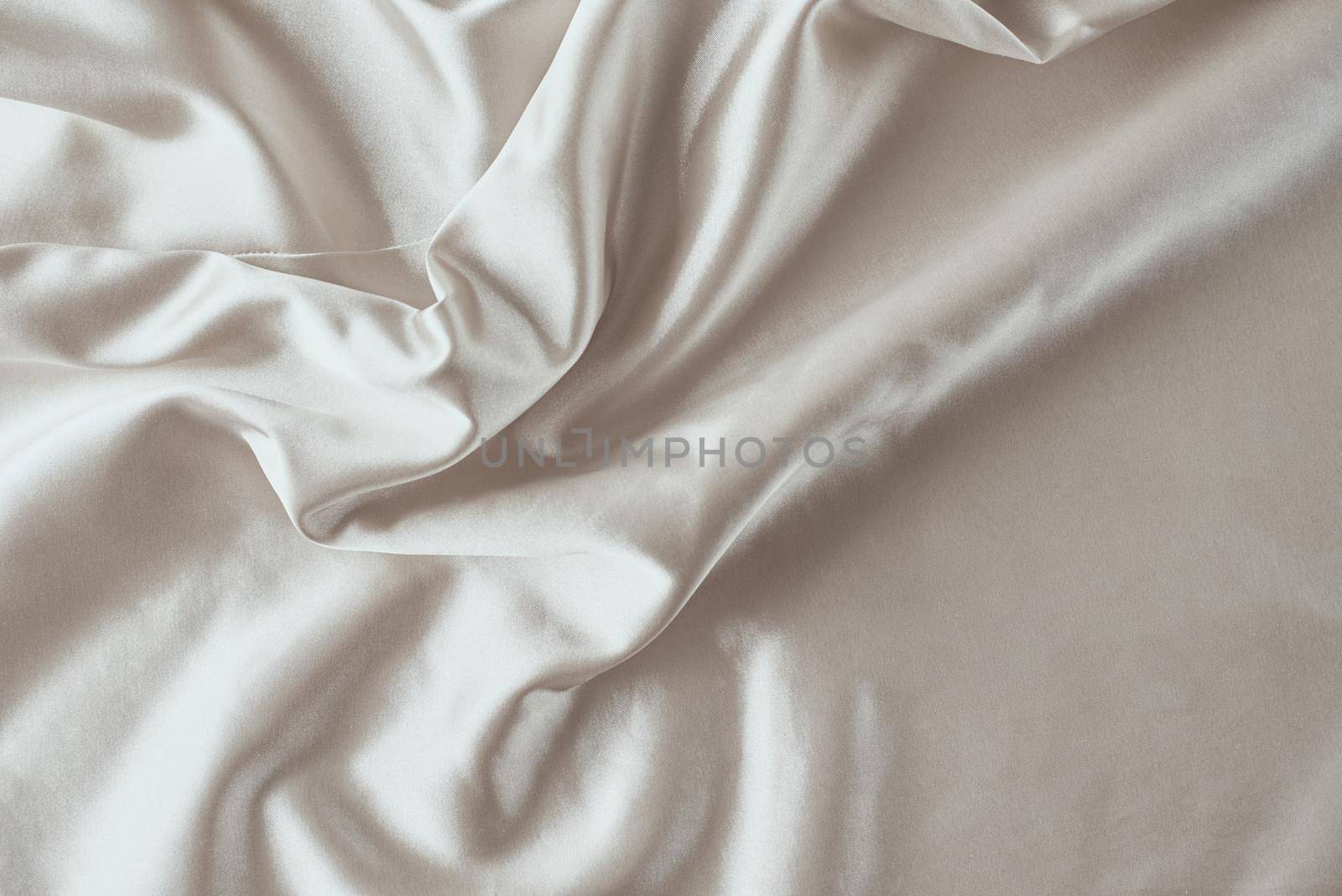 Golden light silk background with folds. Abstract texture of rippled satin surface
