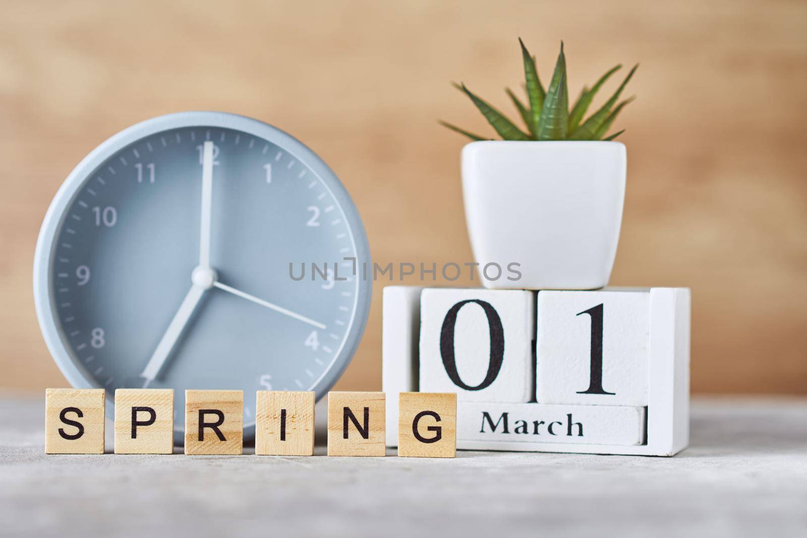 Alarm clock with wooden block calendar date 1st march and plant on table